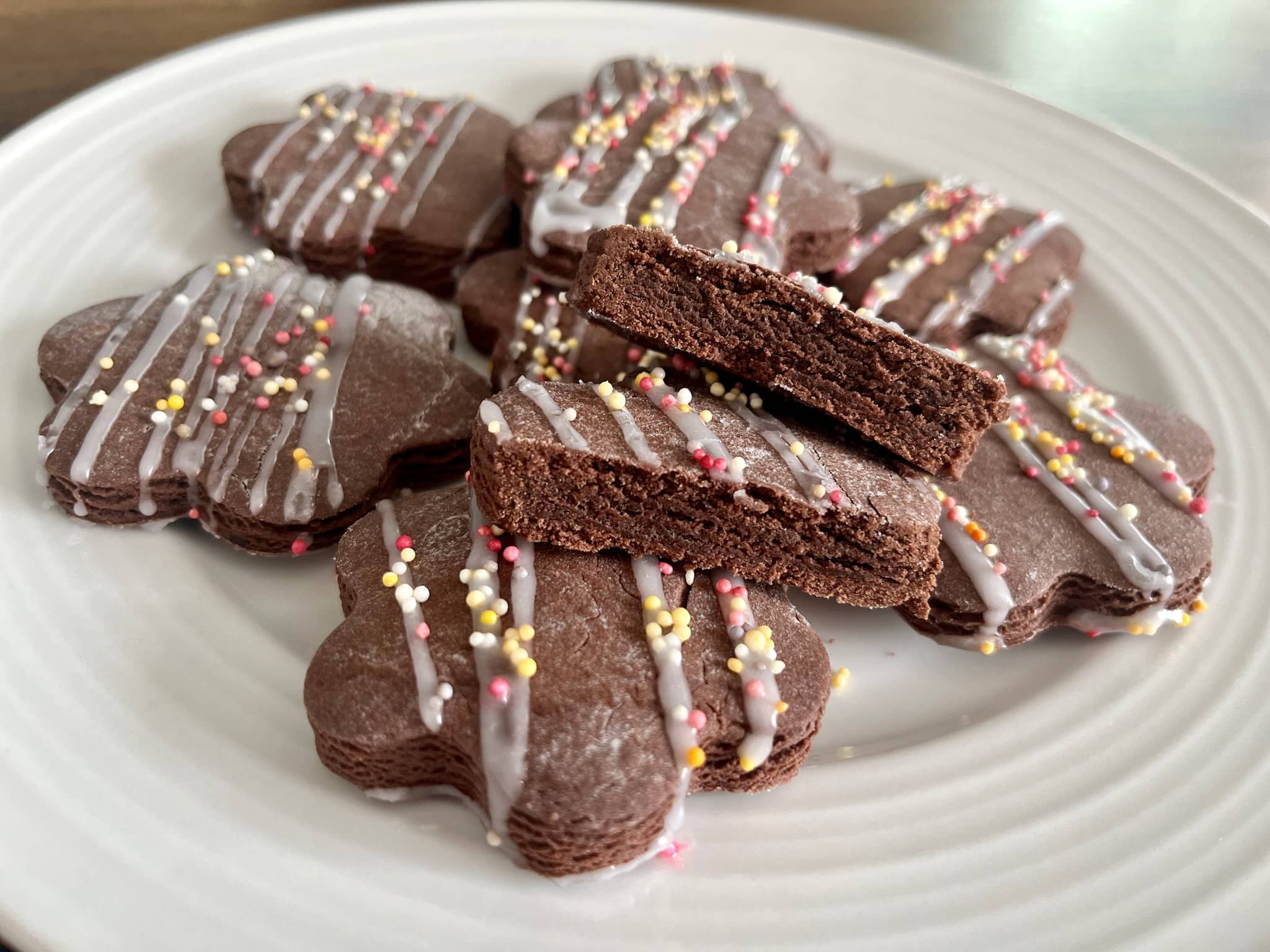 Chocolate cookies decorated with icing sugar and sprinkles showing inside