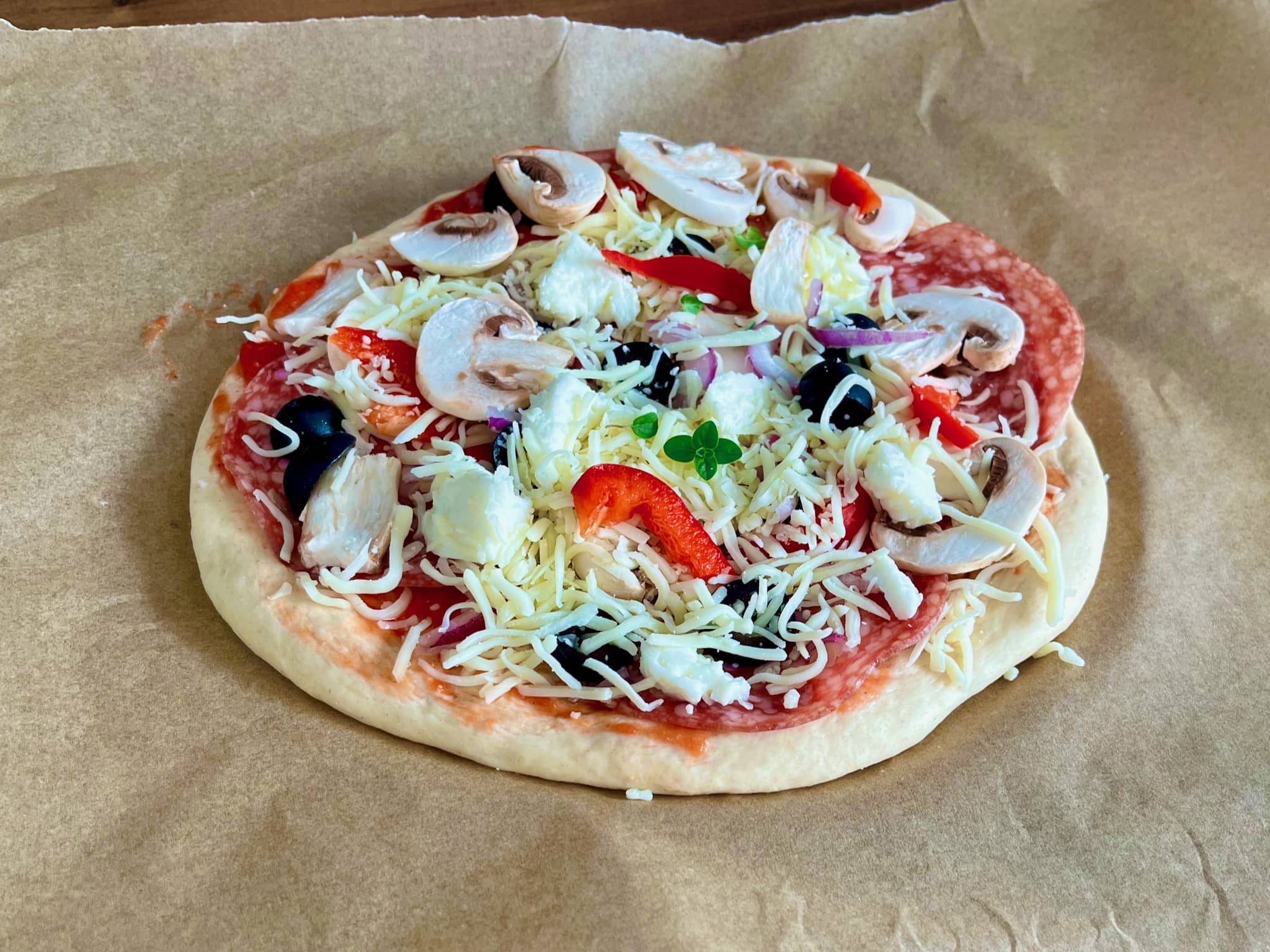Pizza base with sauce and toppings