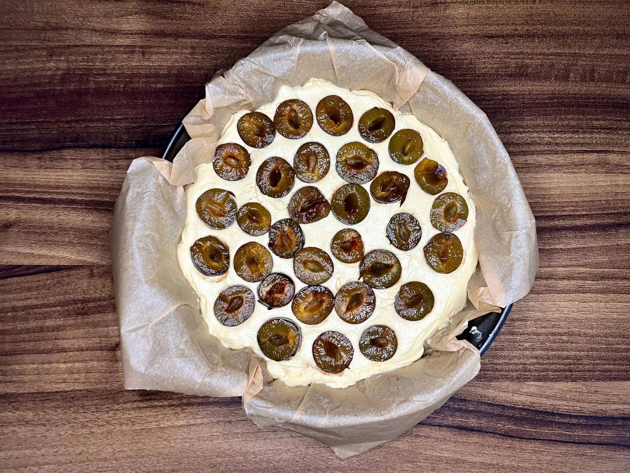 Ciasto w formie, ułożone połówki śliwek, gotowe do pieczenia