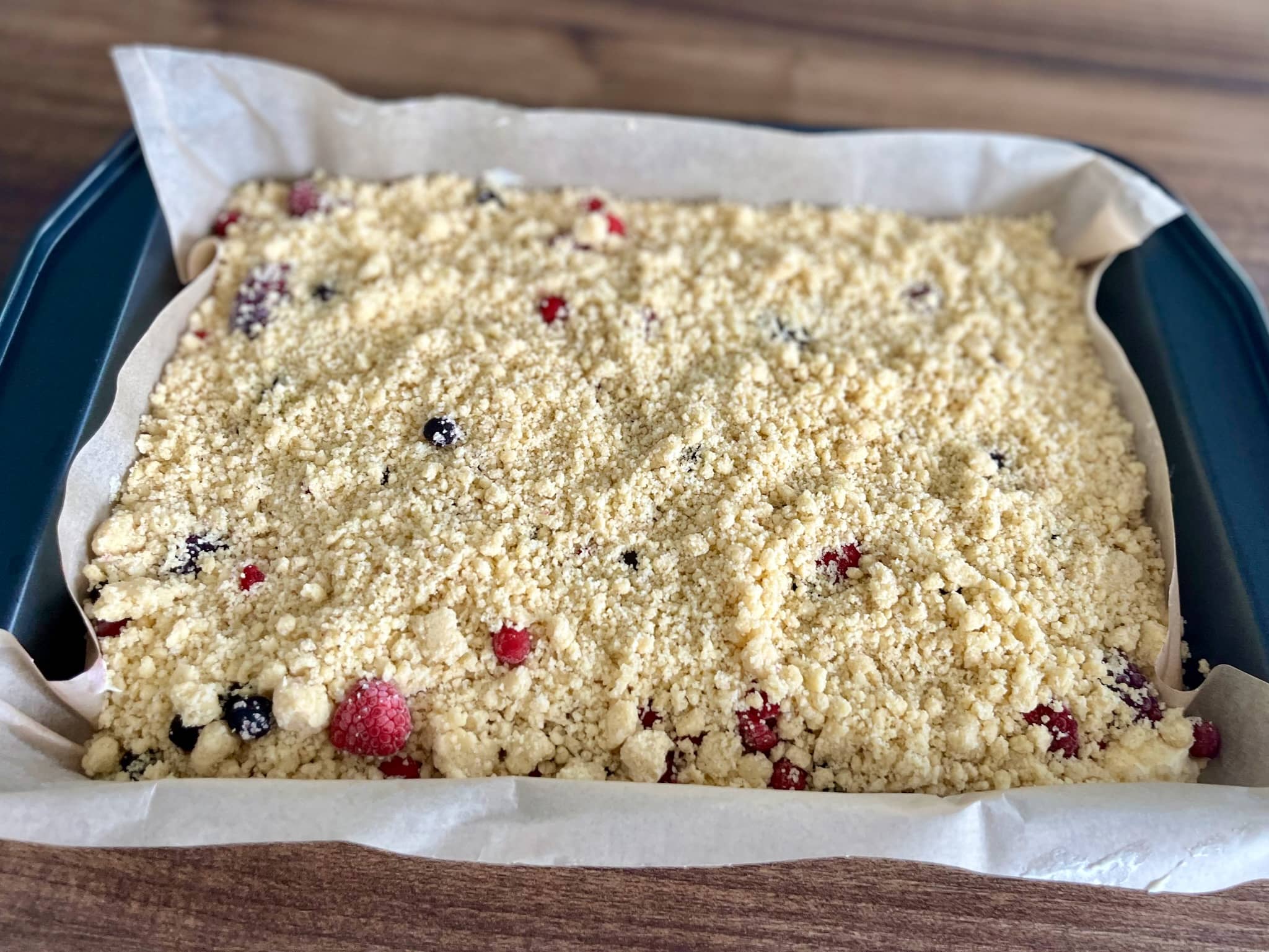 The prepared summer berry crumble cake is ready to be baked
