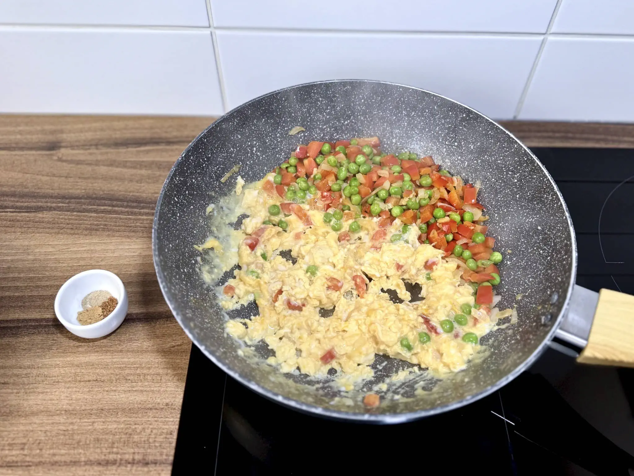 Fried eggs on the side of the vegetables in the pan