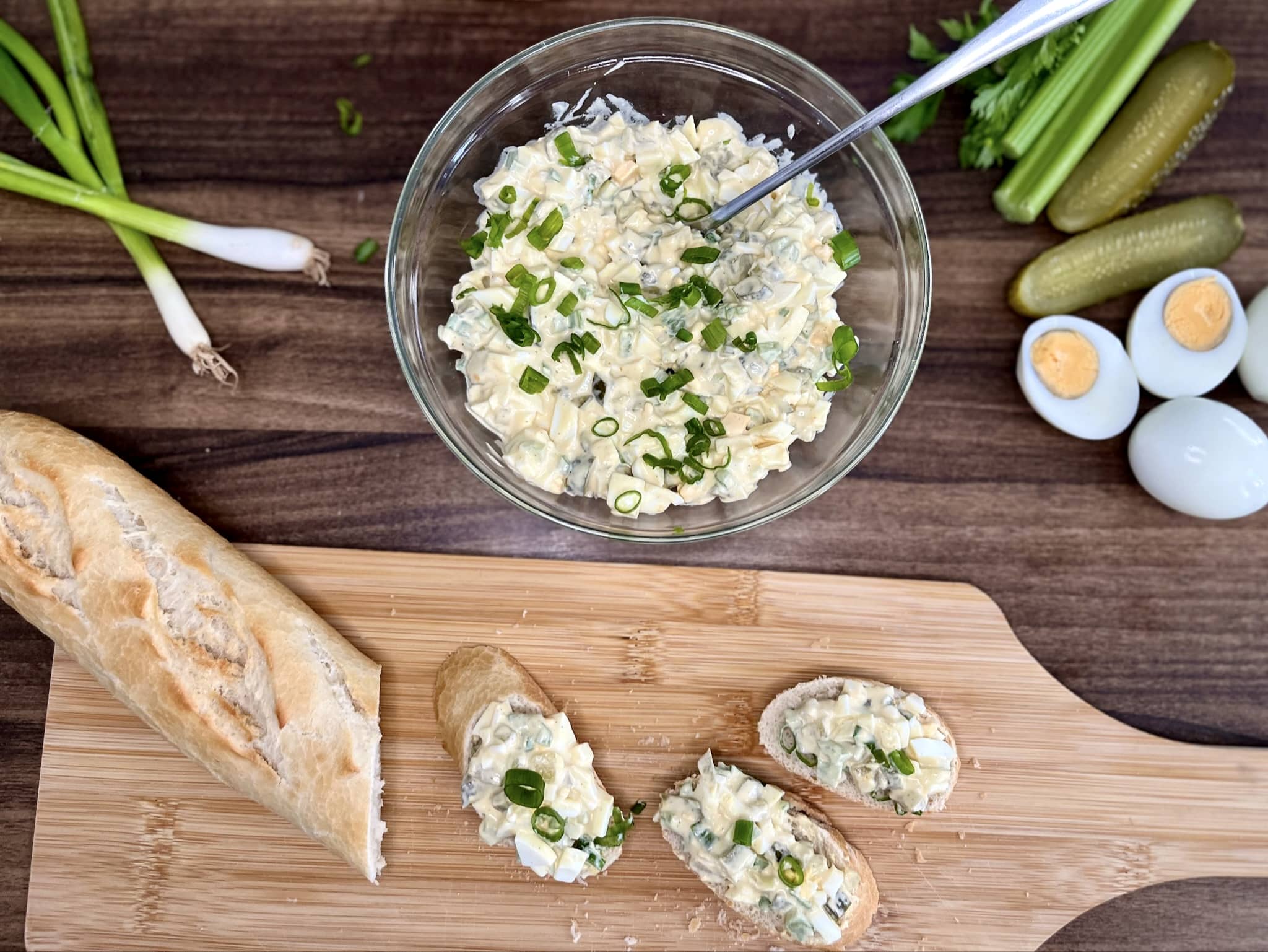 Portion of Egg Mayo with Gherkins Sandwich Filling on a baguette, sliced on a chopping board