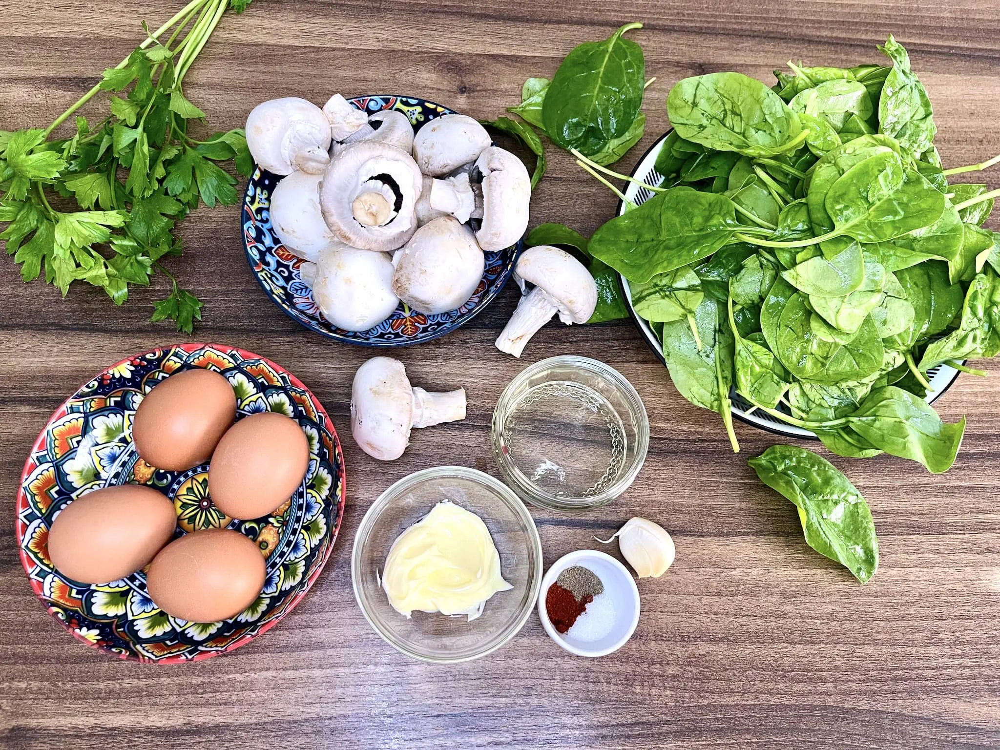 All ingredients for an egg, mushroom, and spinach skillet on the tabletop