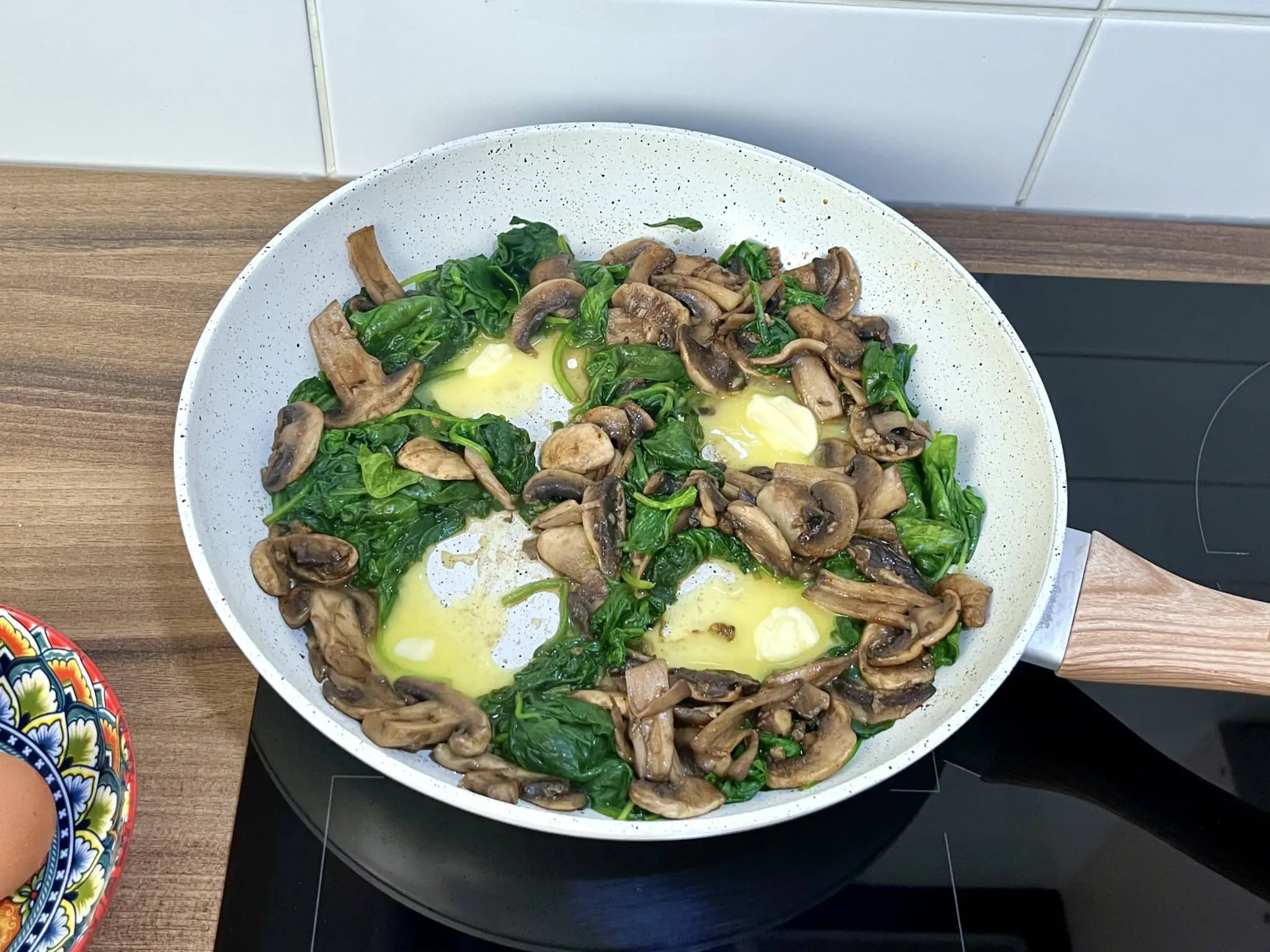 Four wells made in the spinach and mushroom mixture, with added butter