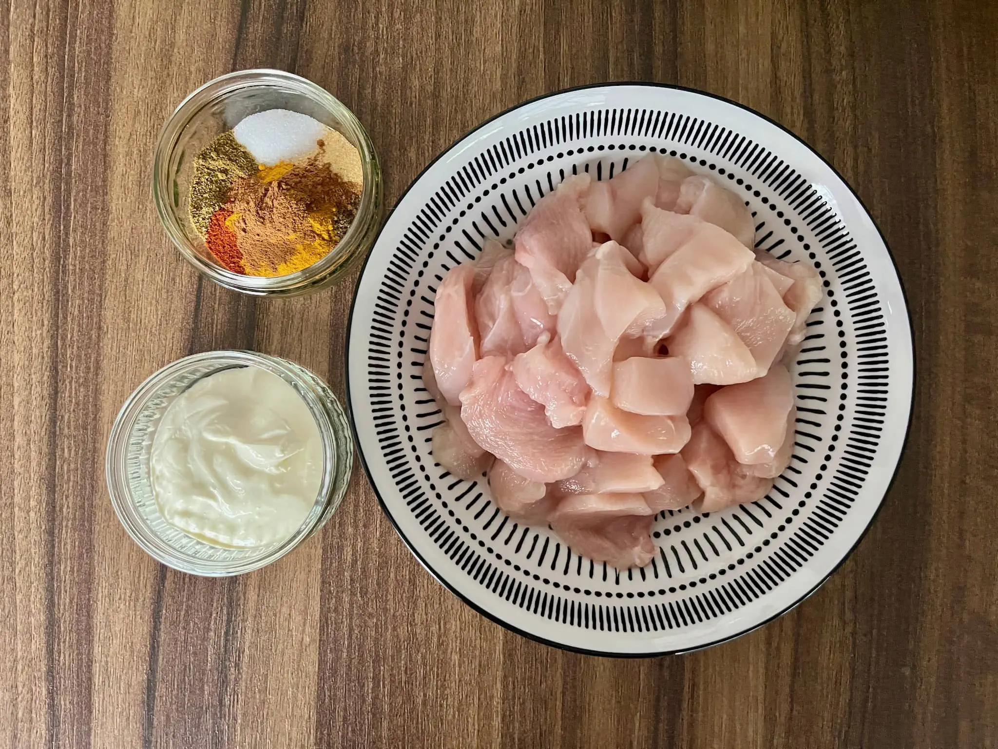 Pokrojony kurczak w misce z przyprawami i jogurtem obok