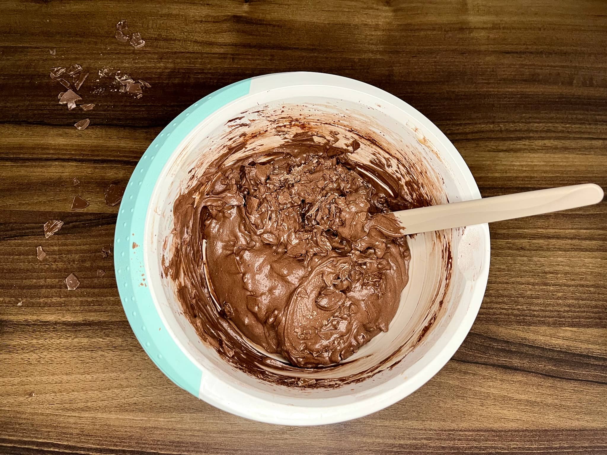 Folding generous chunks of chocolate into the mixed batter in a mixing bowl