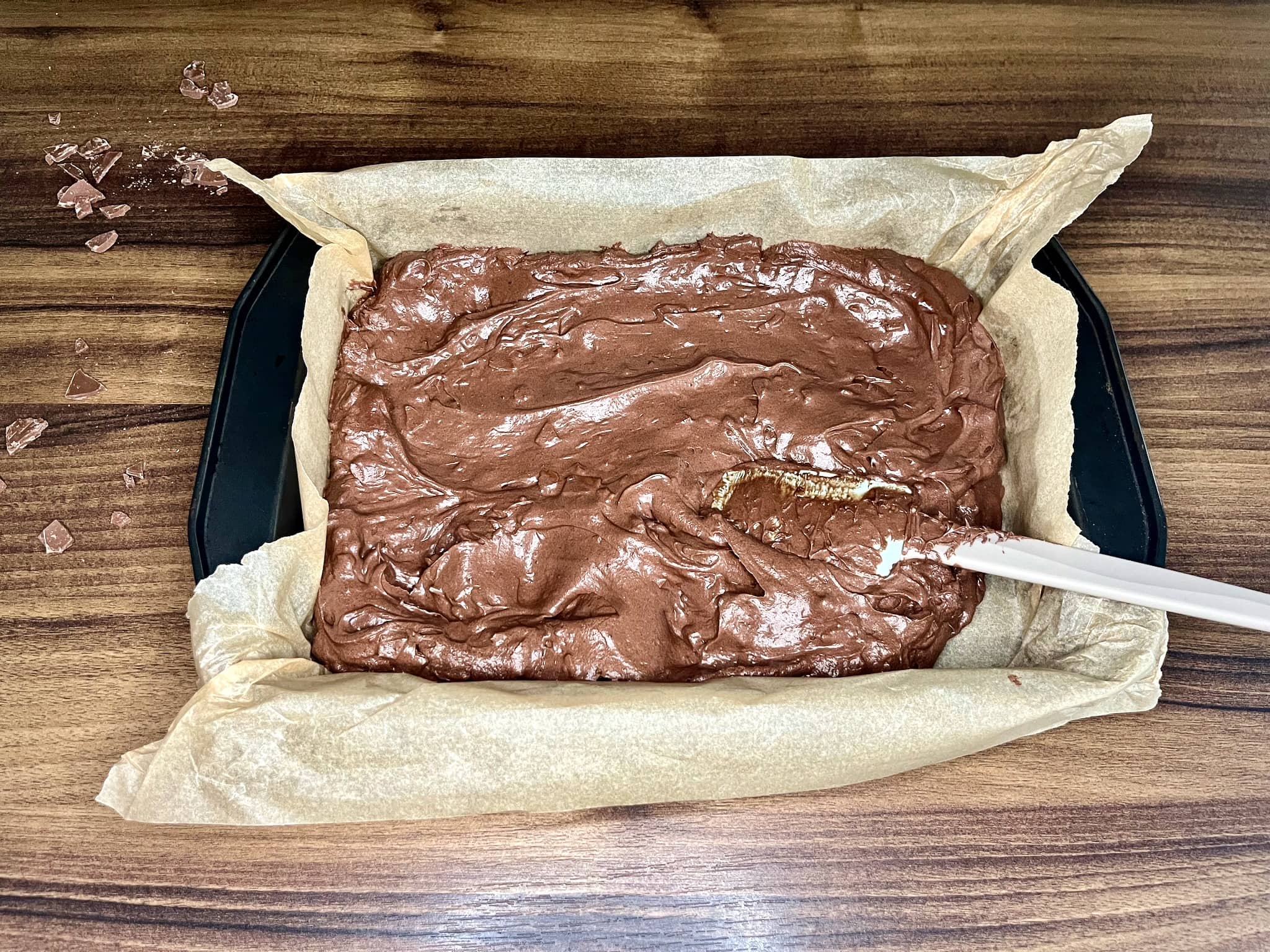 Spreading the brownie batter evenly across the prepared baking tray