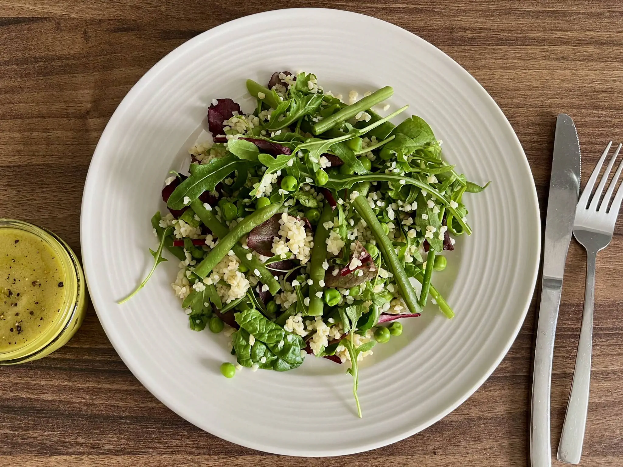 Green Bulgur Salad on a plate with mustard dressing on a side in a sauce glass