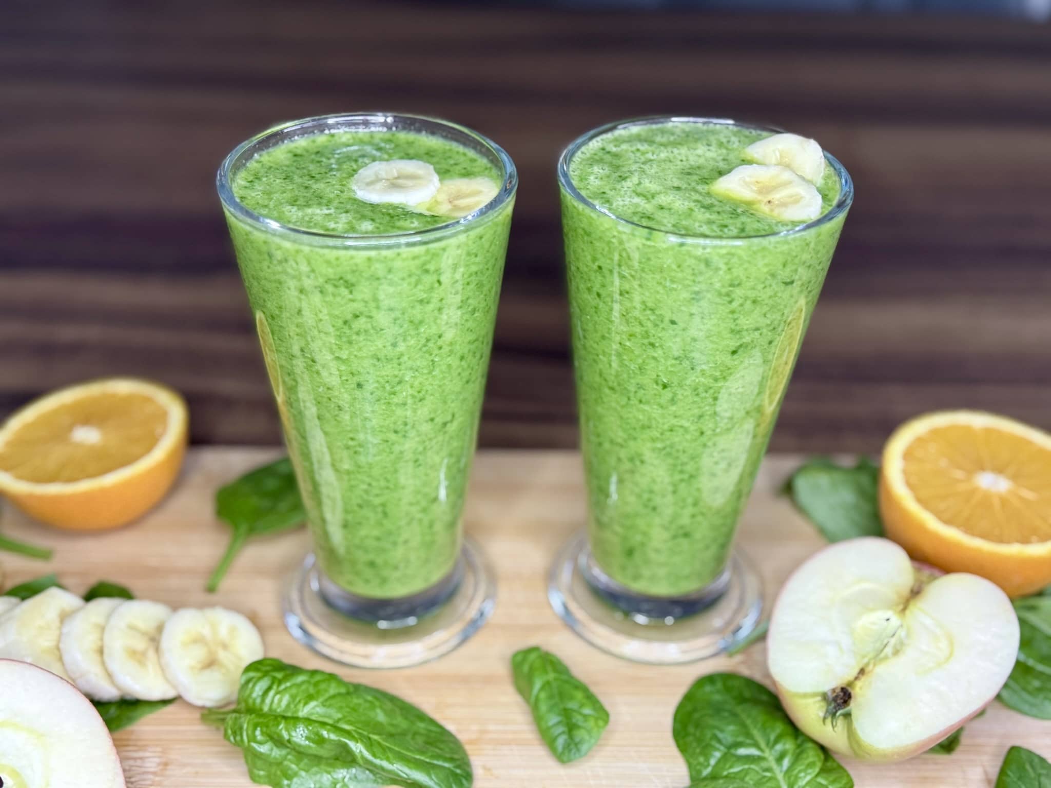 Ready Green Smoothie with Spinach in tall glasses, decorated with slices of banana