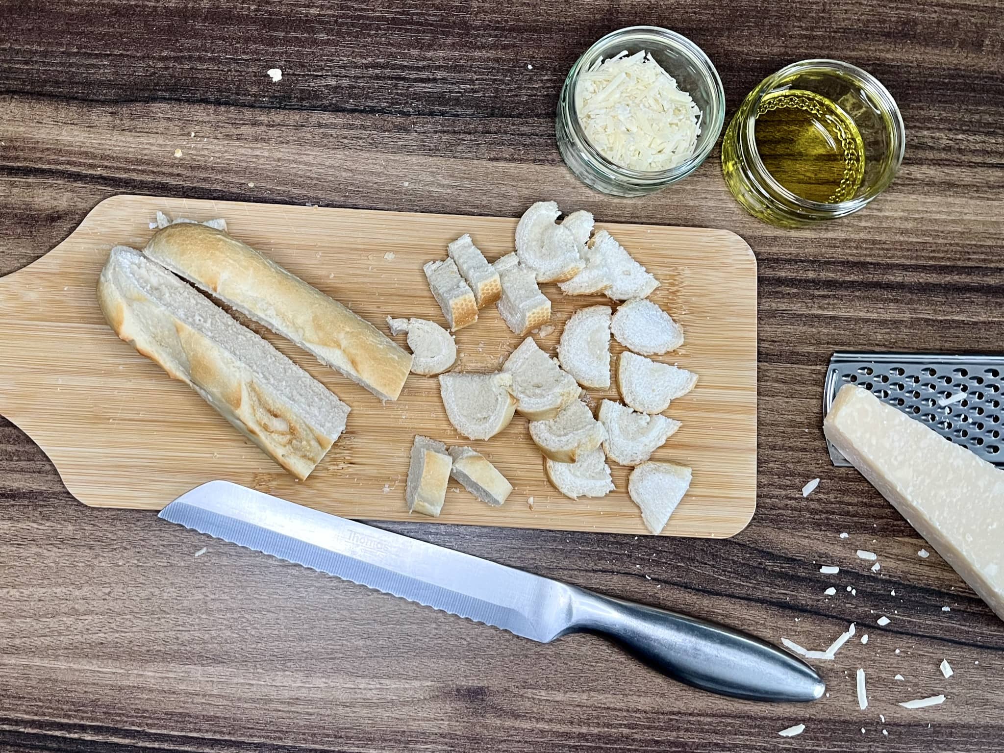 Bagietka na desce do krojenia z oliwą z oliwek i Parmezanem w miseczkach obok
