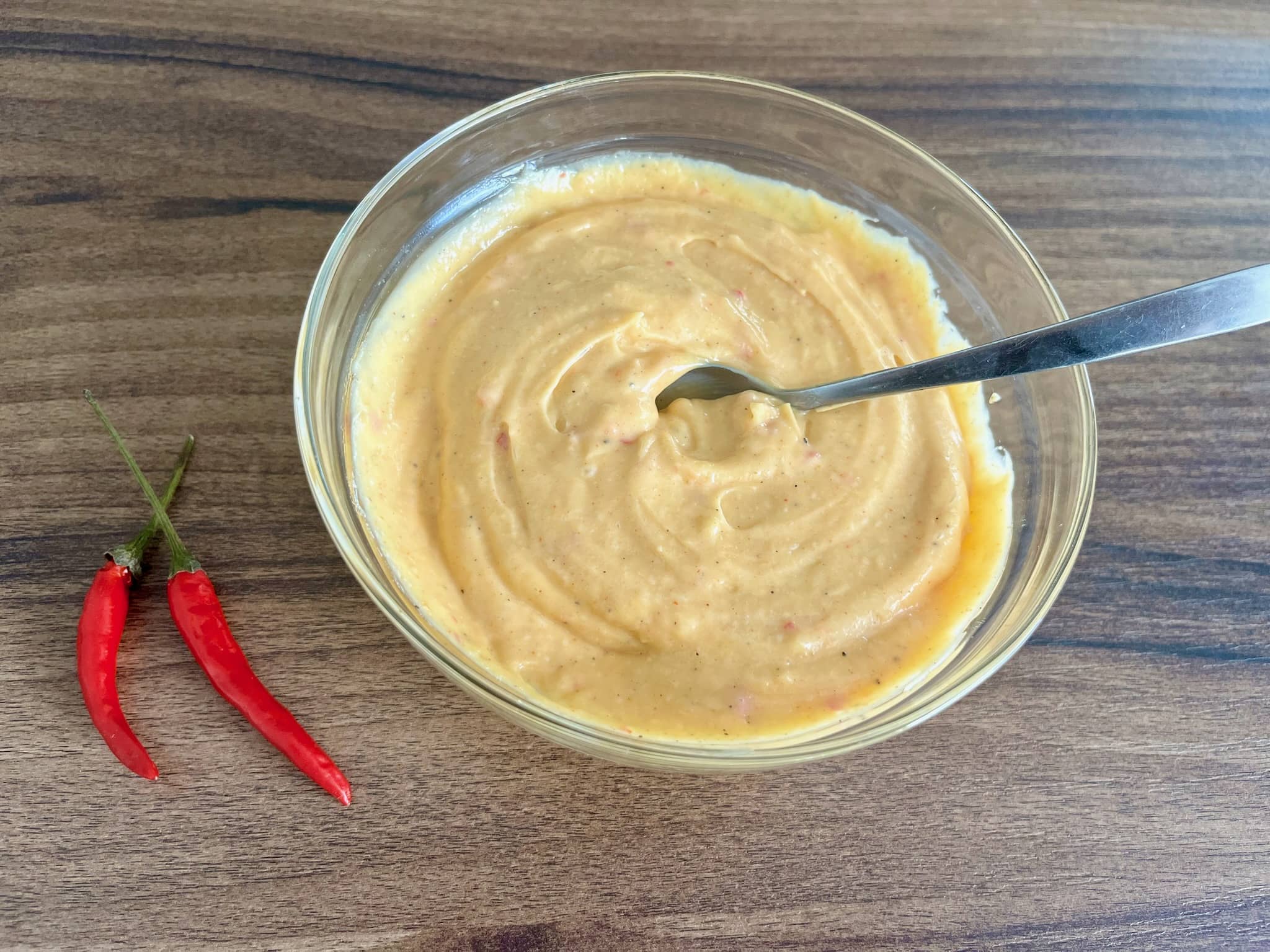 Homemade Spicy Mayonnaise in a bowl with two chilli peppers on a side