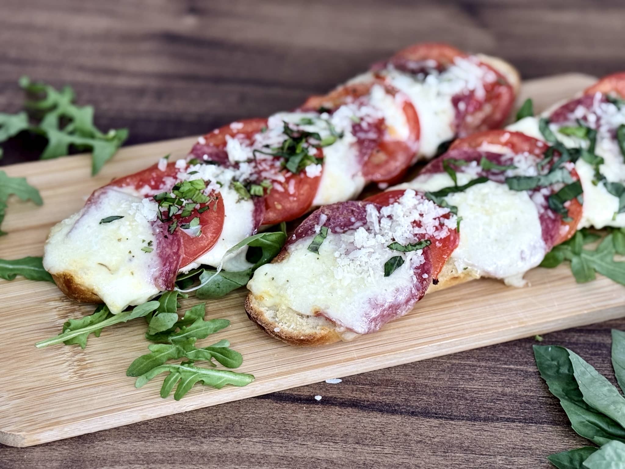 Two Italian-style open-faced sandwiches presented on a chopping board