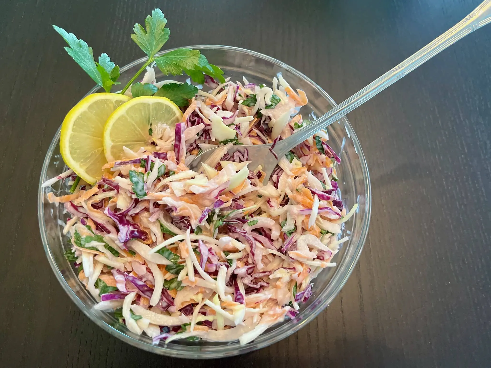 Prosta surówka coleslaw w misce, ozdobiona plastrami cytryny i świeżą pietruszką