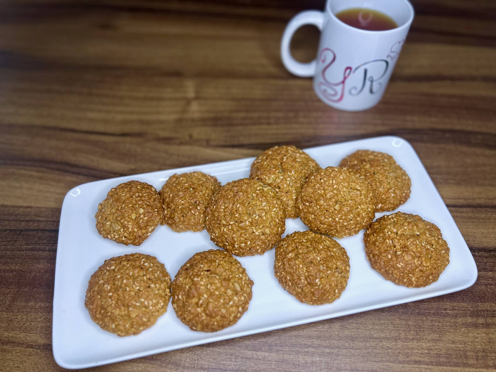 Nicely baked Just Perfect Seeded Oat Cookies on a plate with a mug of tea on a side