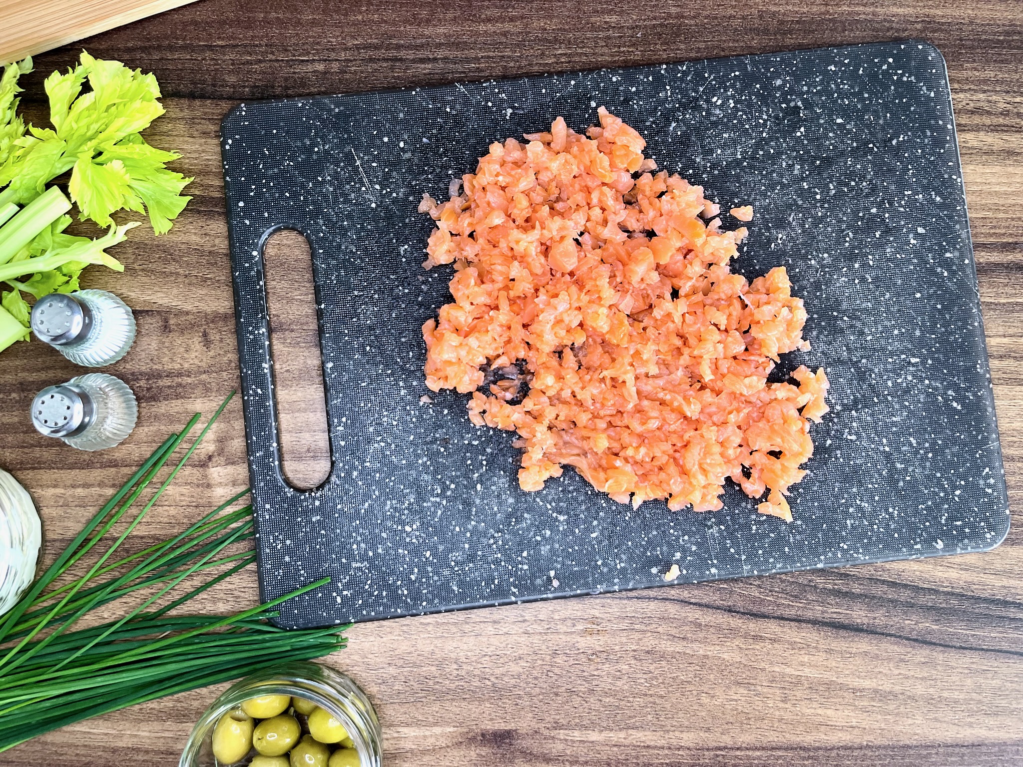 Smoked salmon, finely chopped, rests on a chopping board.
