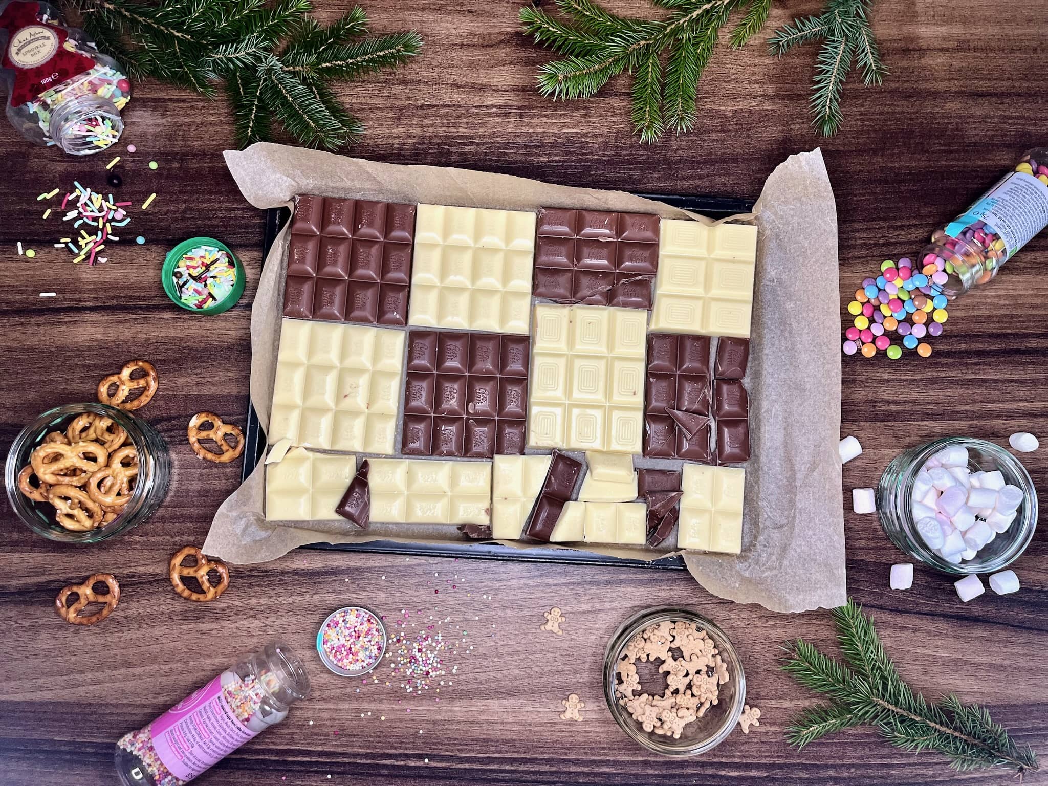Chocolate lined on a baking tray with sprinkles scattered around on the tabletop