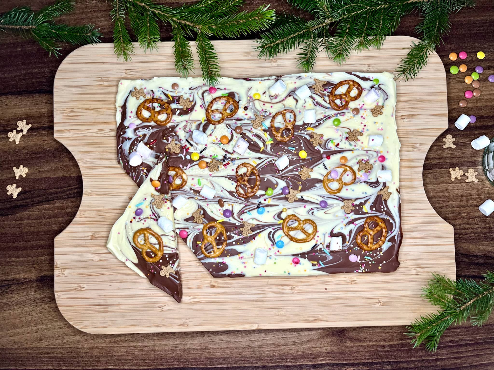 A fully set, decorated chocolate block with sprinkles, resting on a chopping board with a chipped corner