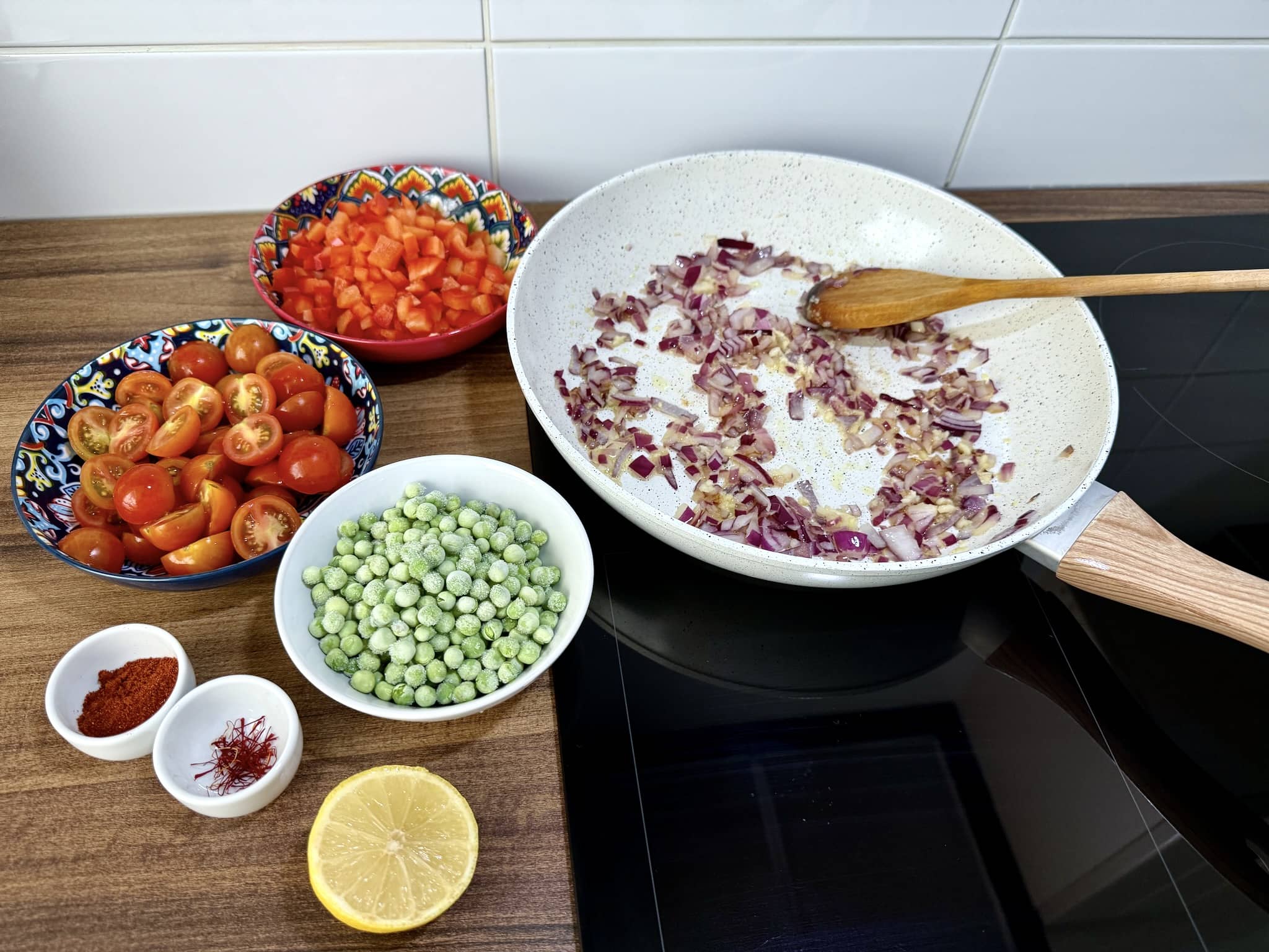 Frying onion in a pan with other ingredients on the side