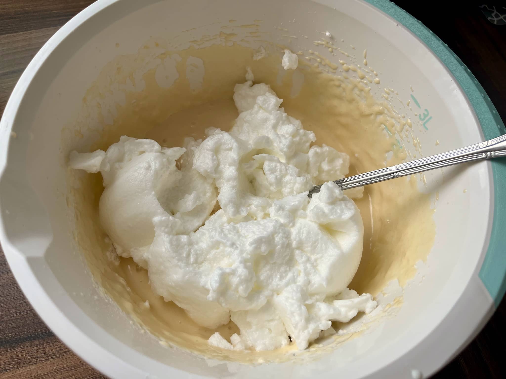 Stiff foam from wgg whites added to the waffle batter in a bowl