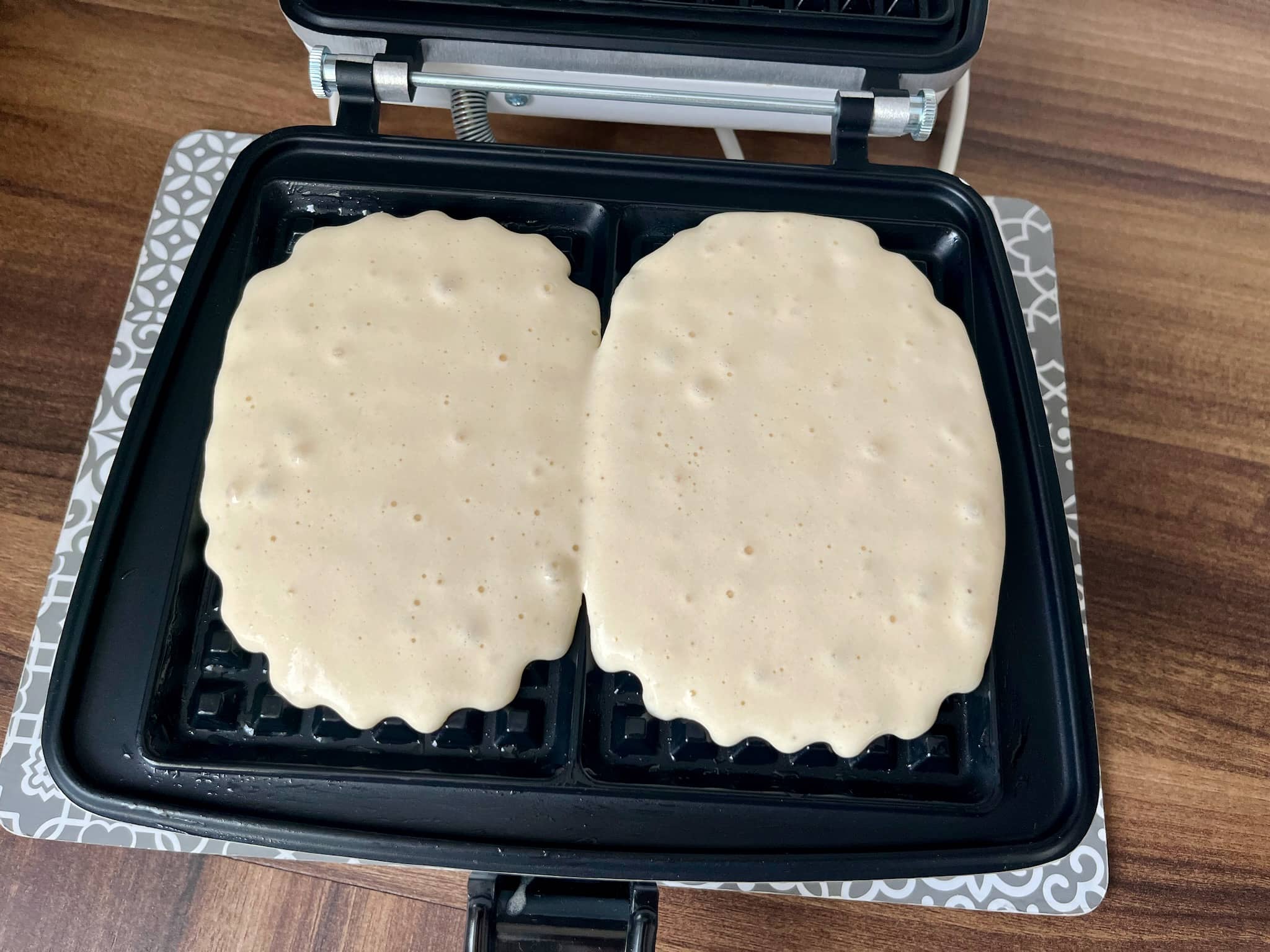 The first portion of waffles frying in a waffle maker