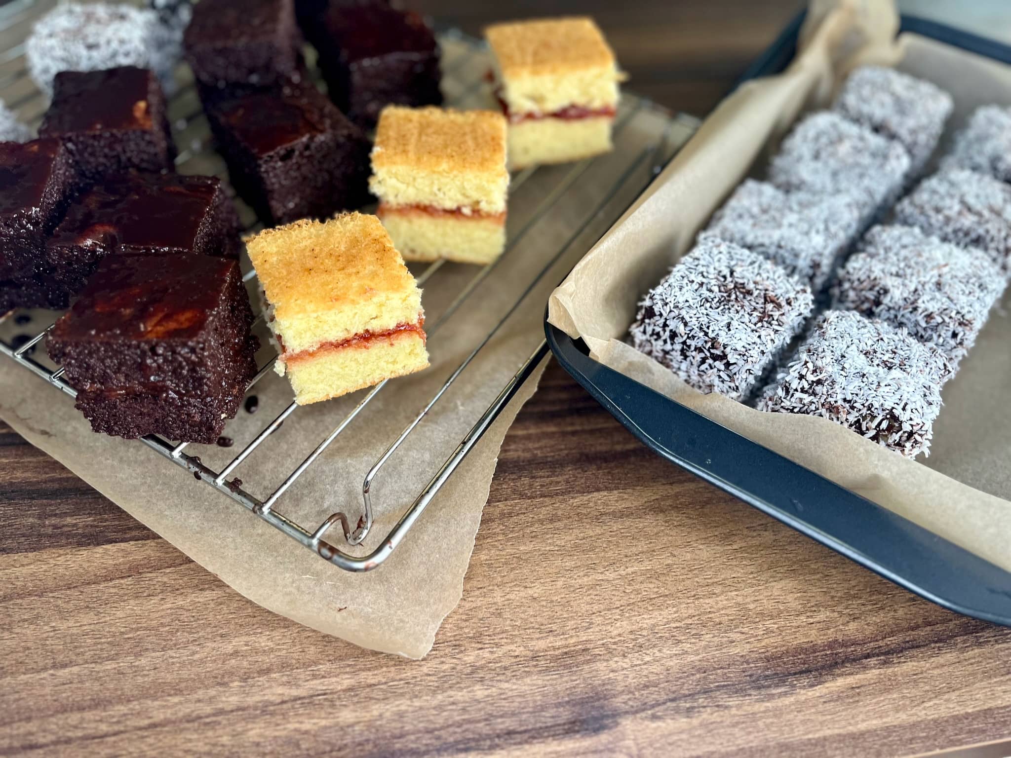 Plain sponge squares, squares coated in chocolate and suares coated in desiccated coconut making Lamingtons
