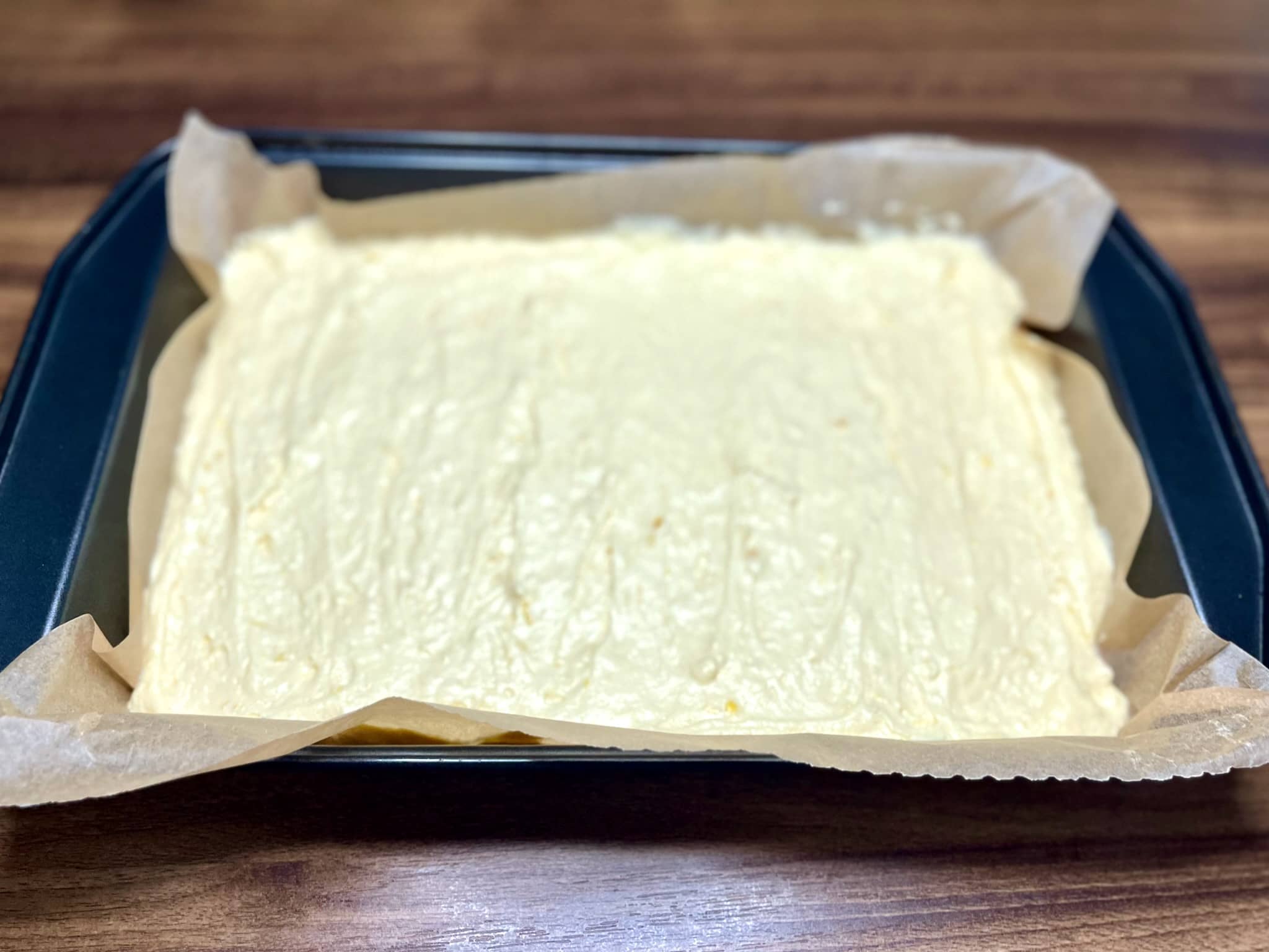 The batter is in a baking tray lined with baking paper