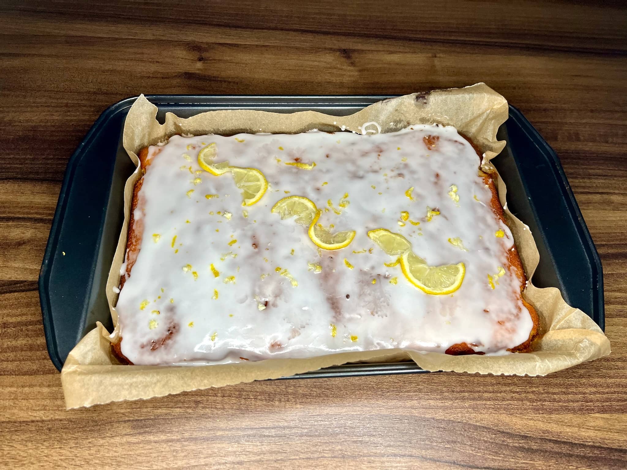 Cake glazed with icing and decorated with lemon zest and lemon slices