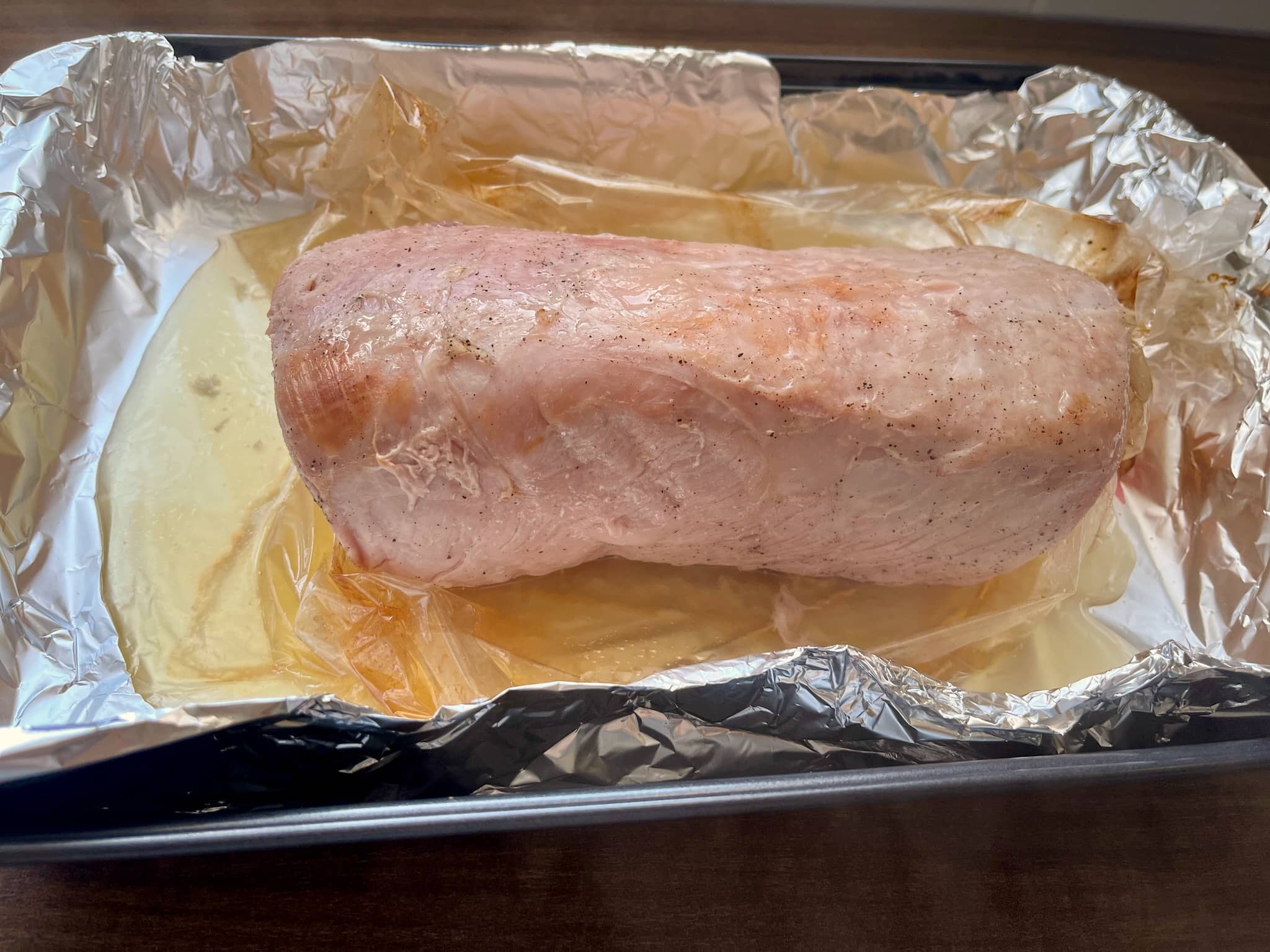 Baked marinated pork loin in an open roasting bag on a tray