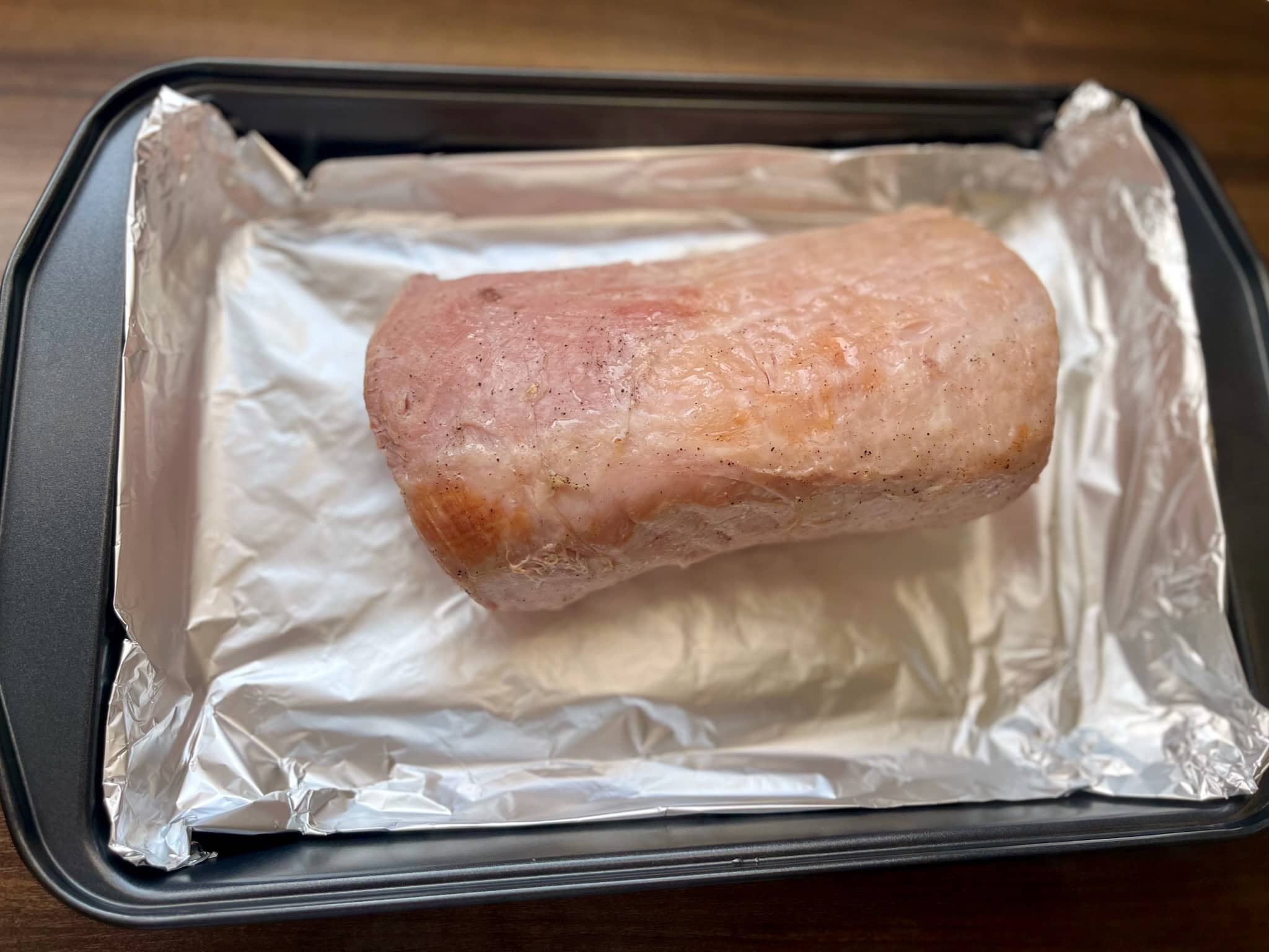 Baked marinated pork loin on a baking tray with fresh aluminium foil
