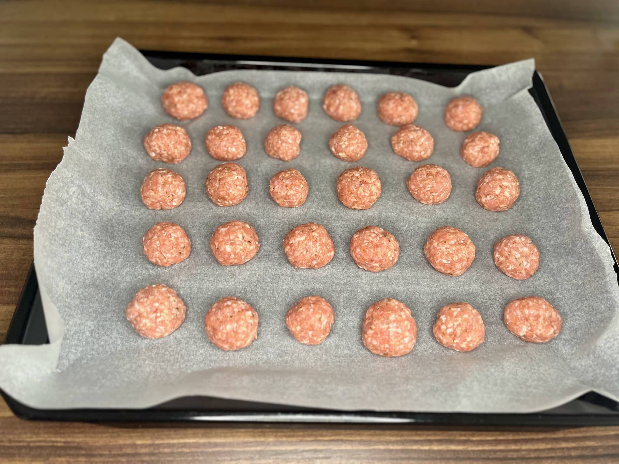 Formed meatballs the size of a golf ball on a baking tray