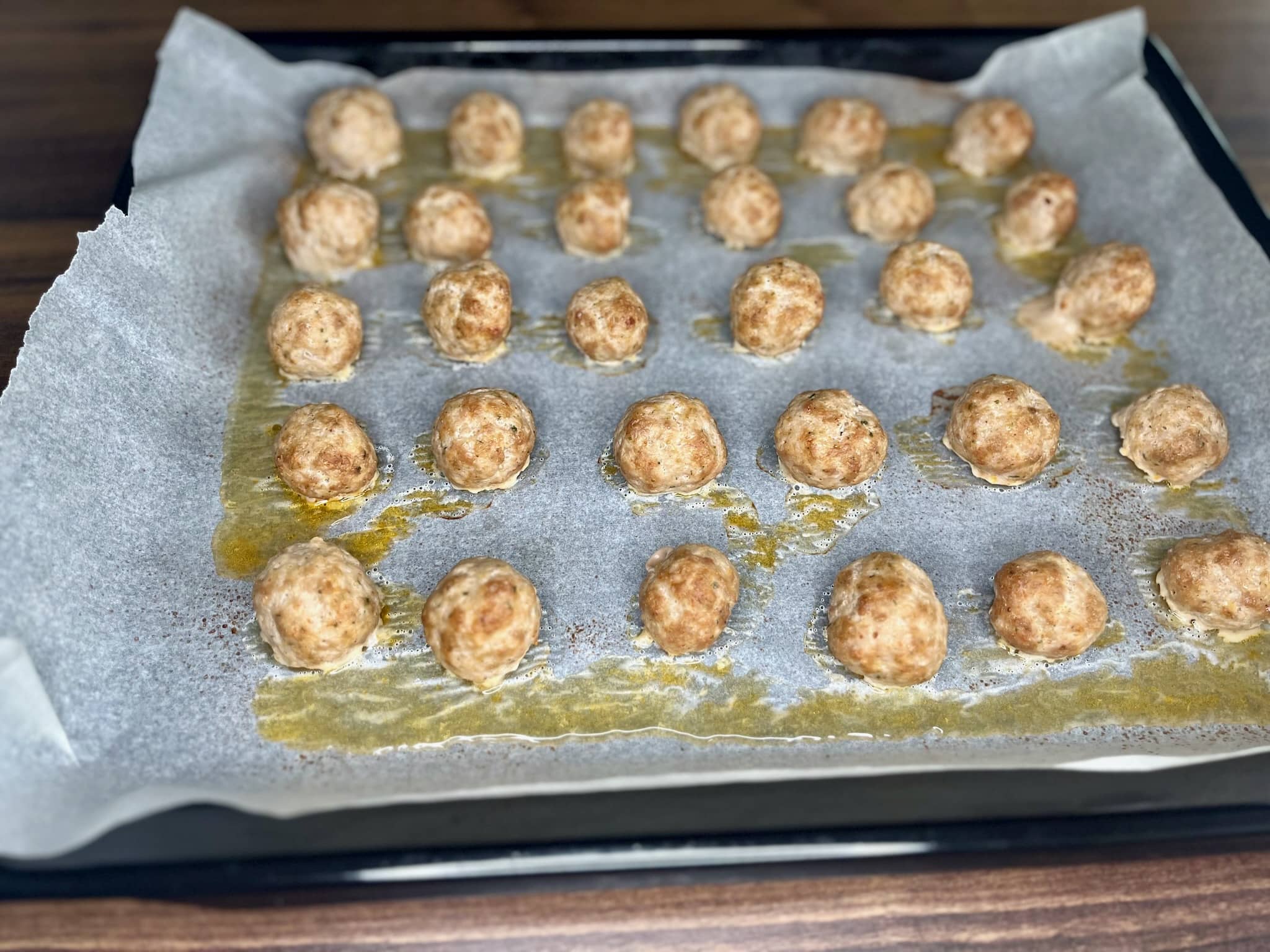 The nicely browned meatballs are still on the baking tray