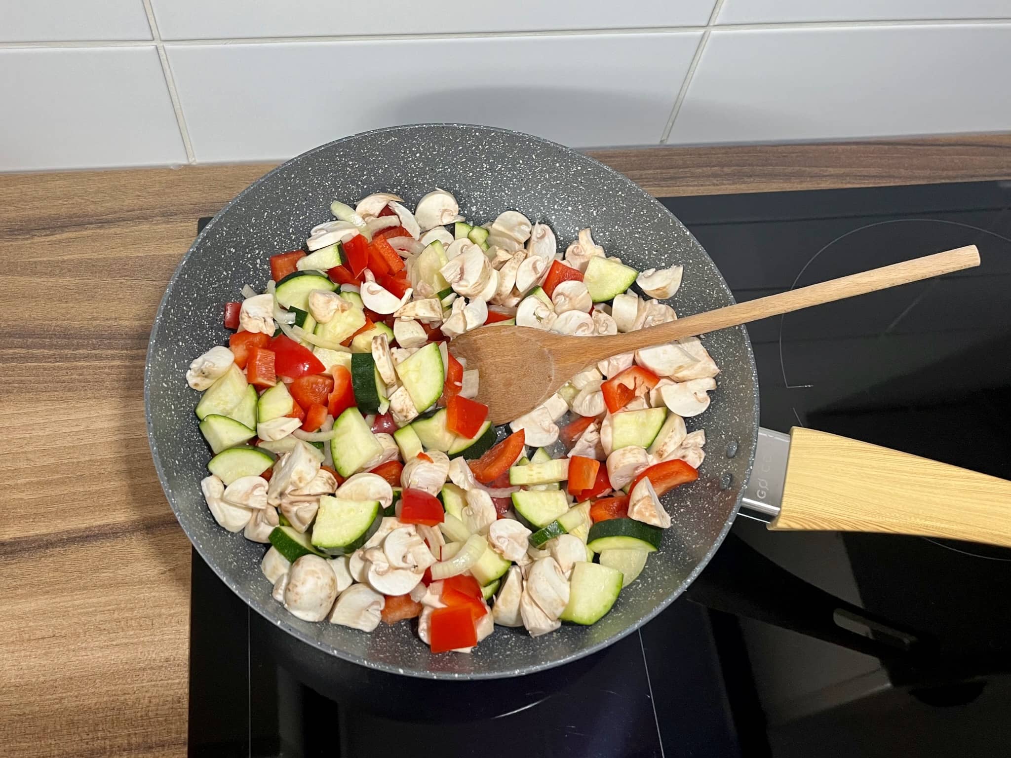 A large pan is filled with chopped vegetables, ready to be fried.