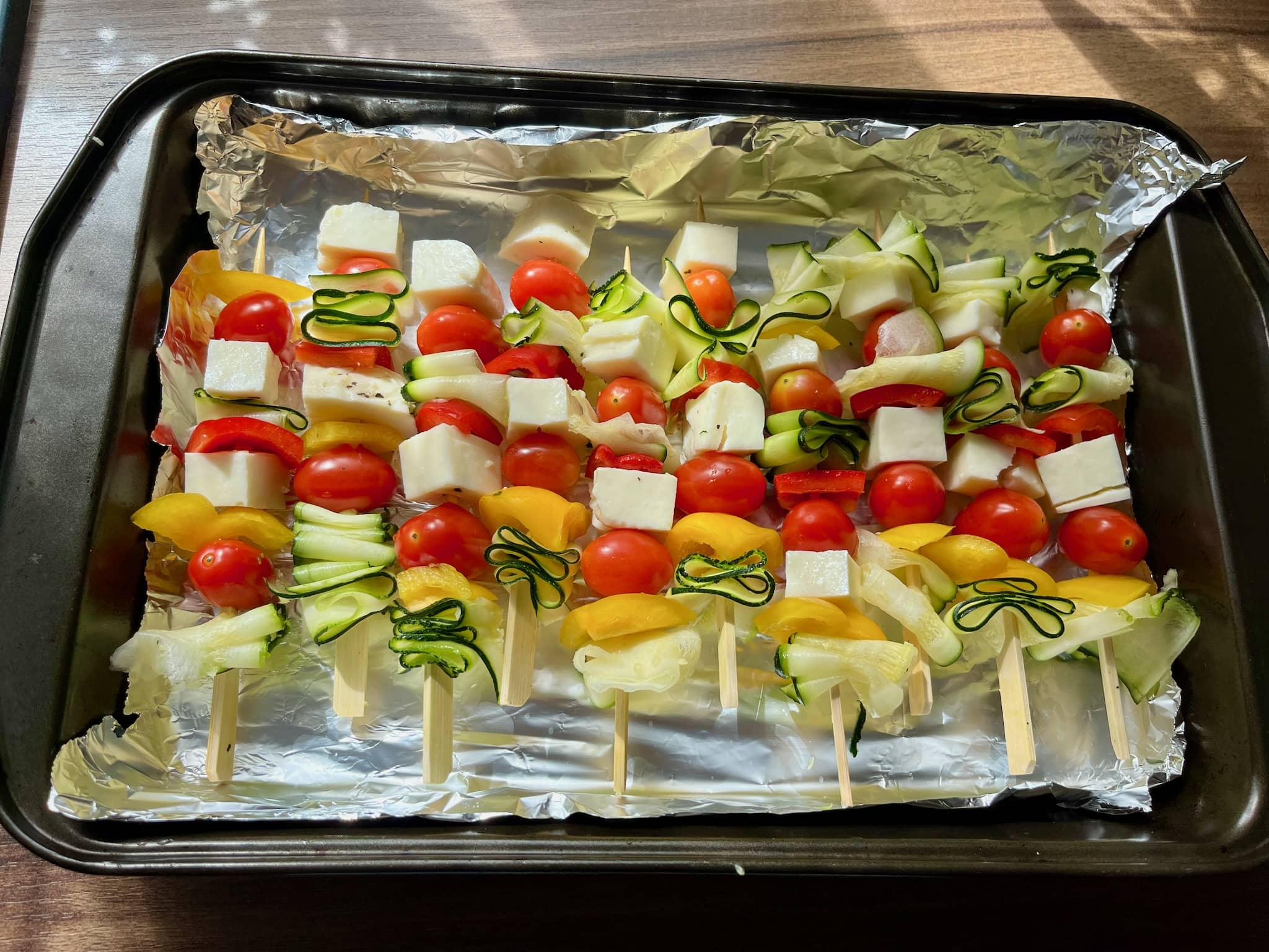 Stuffed pieces of vegetables and chees on skewers placed on a baking tray