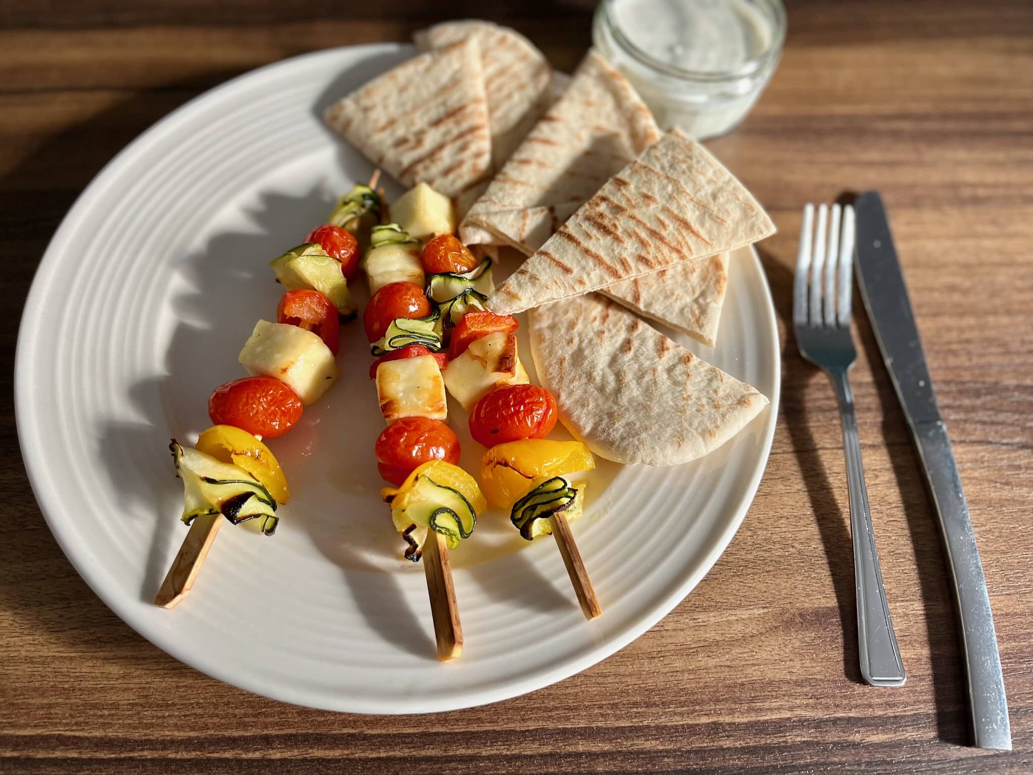 Ready baked Meatless Skewers with Halloumi Cheese on a plate with Pitta Bread and dip on a side