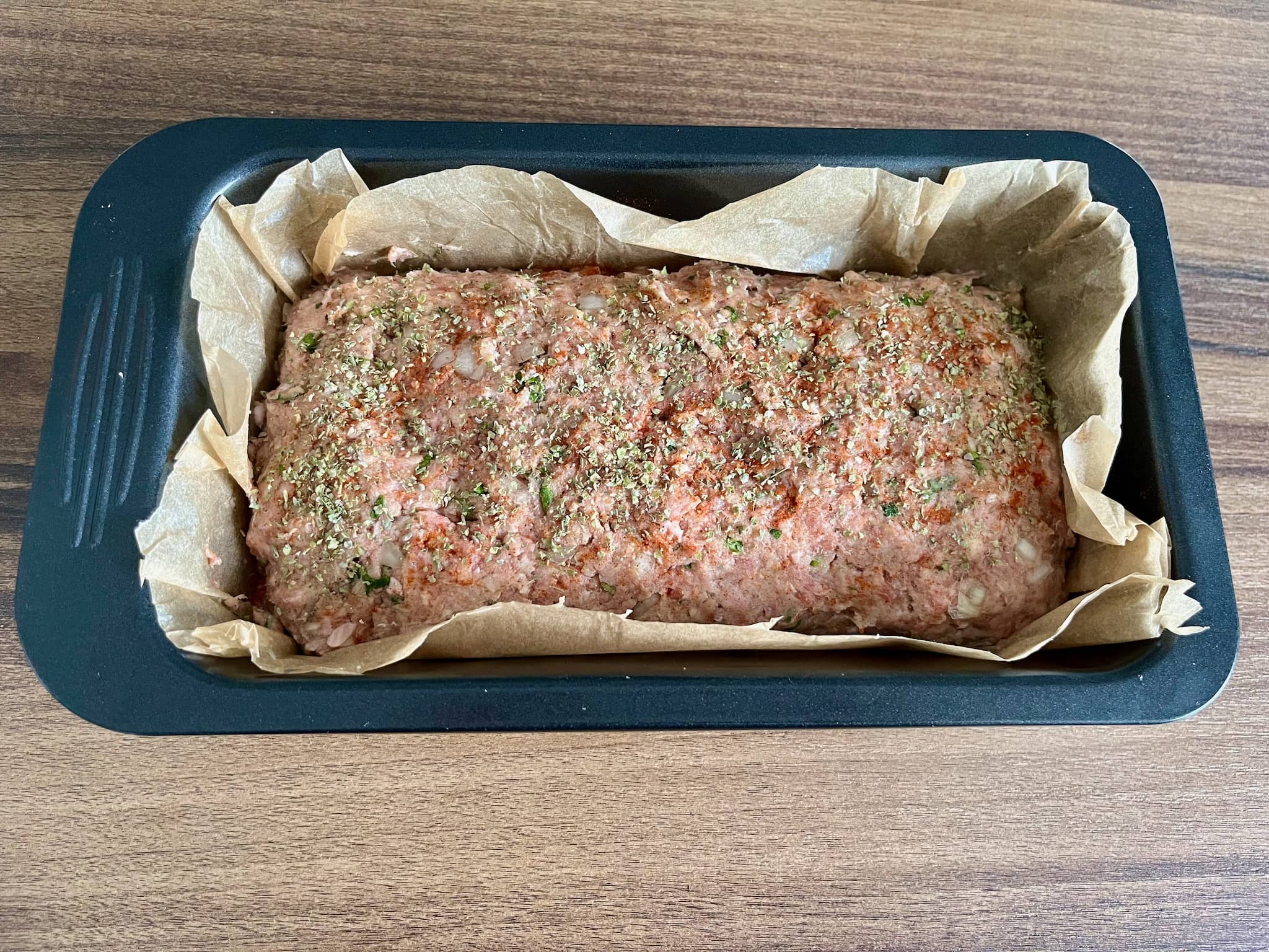 Meatloaf sprinkled with ground paprika and marjoram ready to be baked