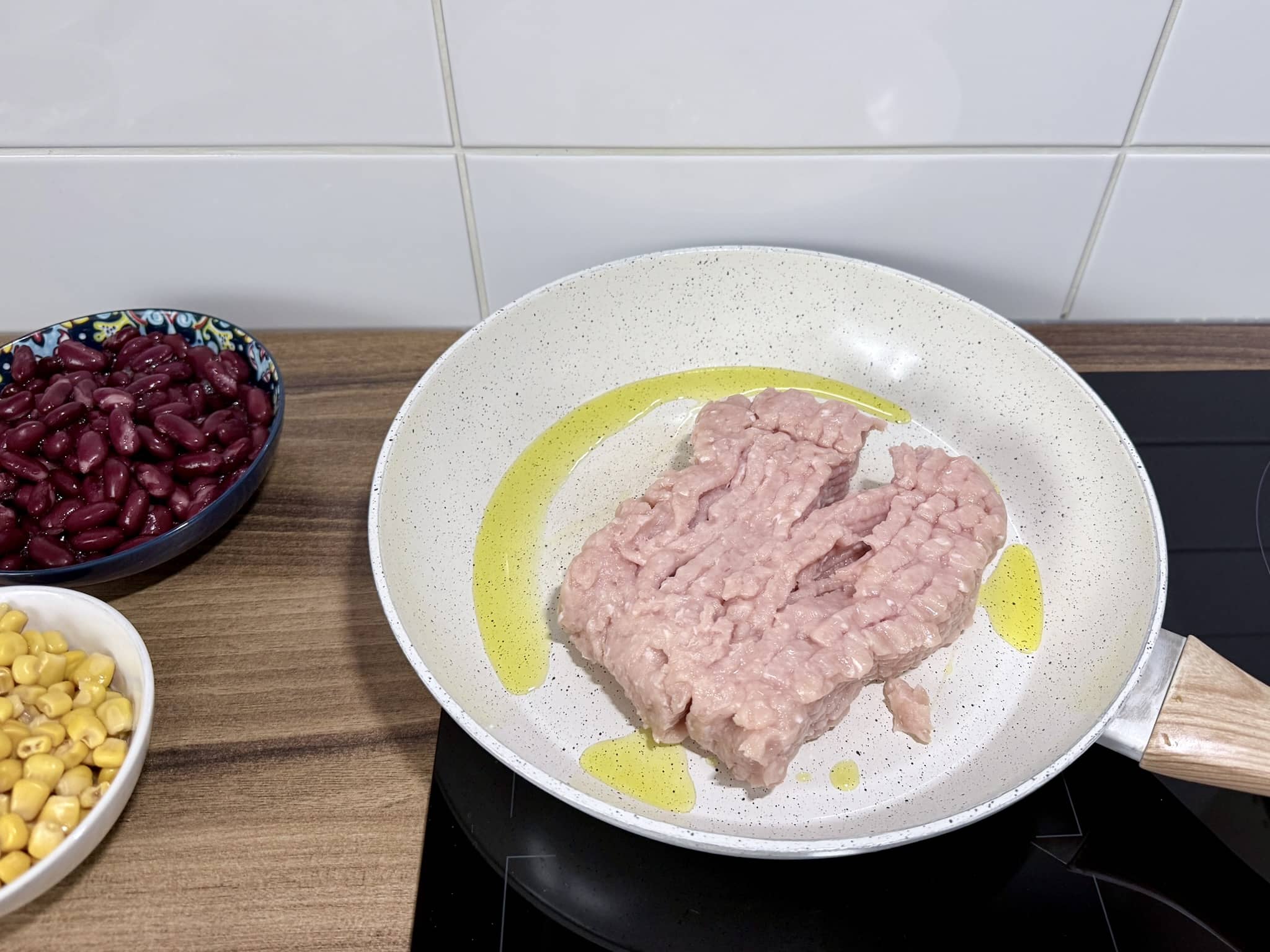 Chicken mince placed in a skillet filled with olive oil