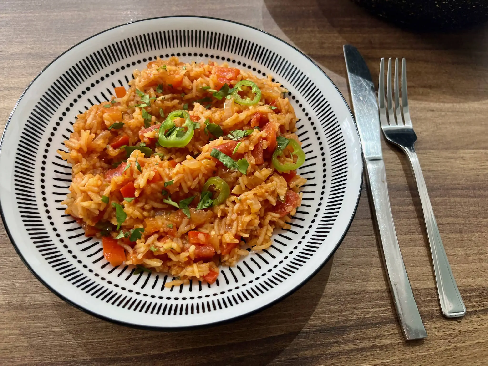 Mexican Rice on a plate decorated with jalapeño slices and coriander