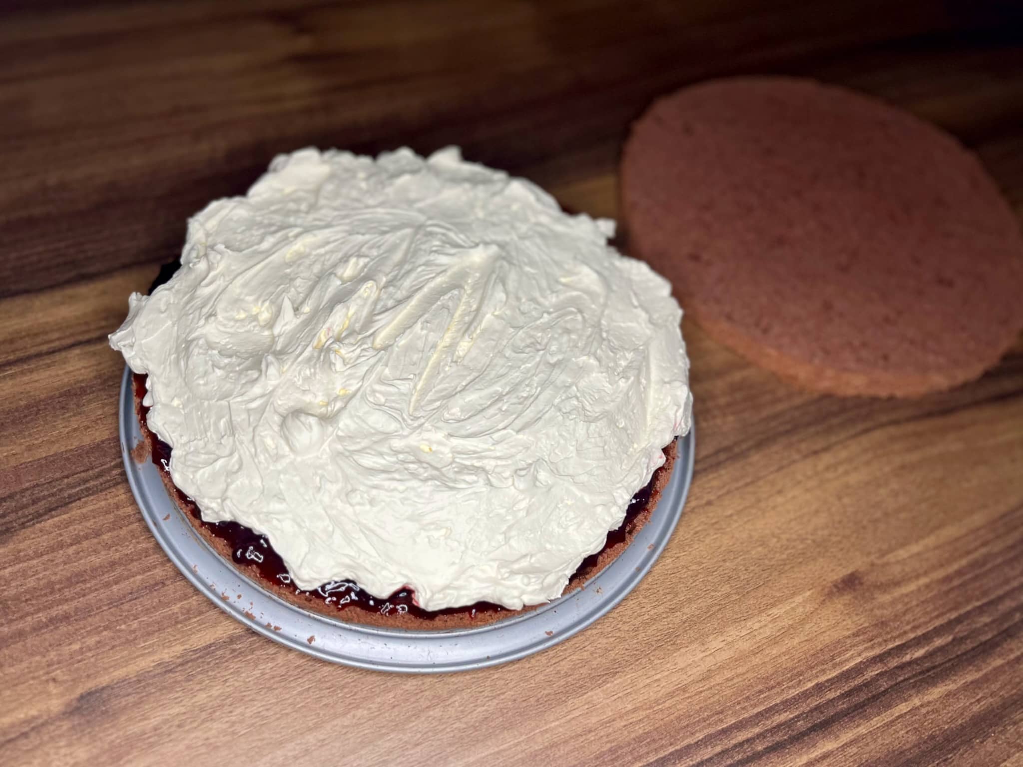 The bottom part of the cake is covered with whipped cream on top of jam