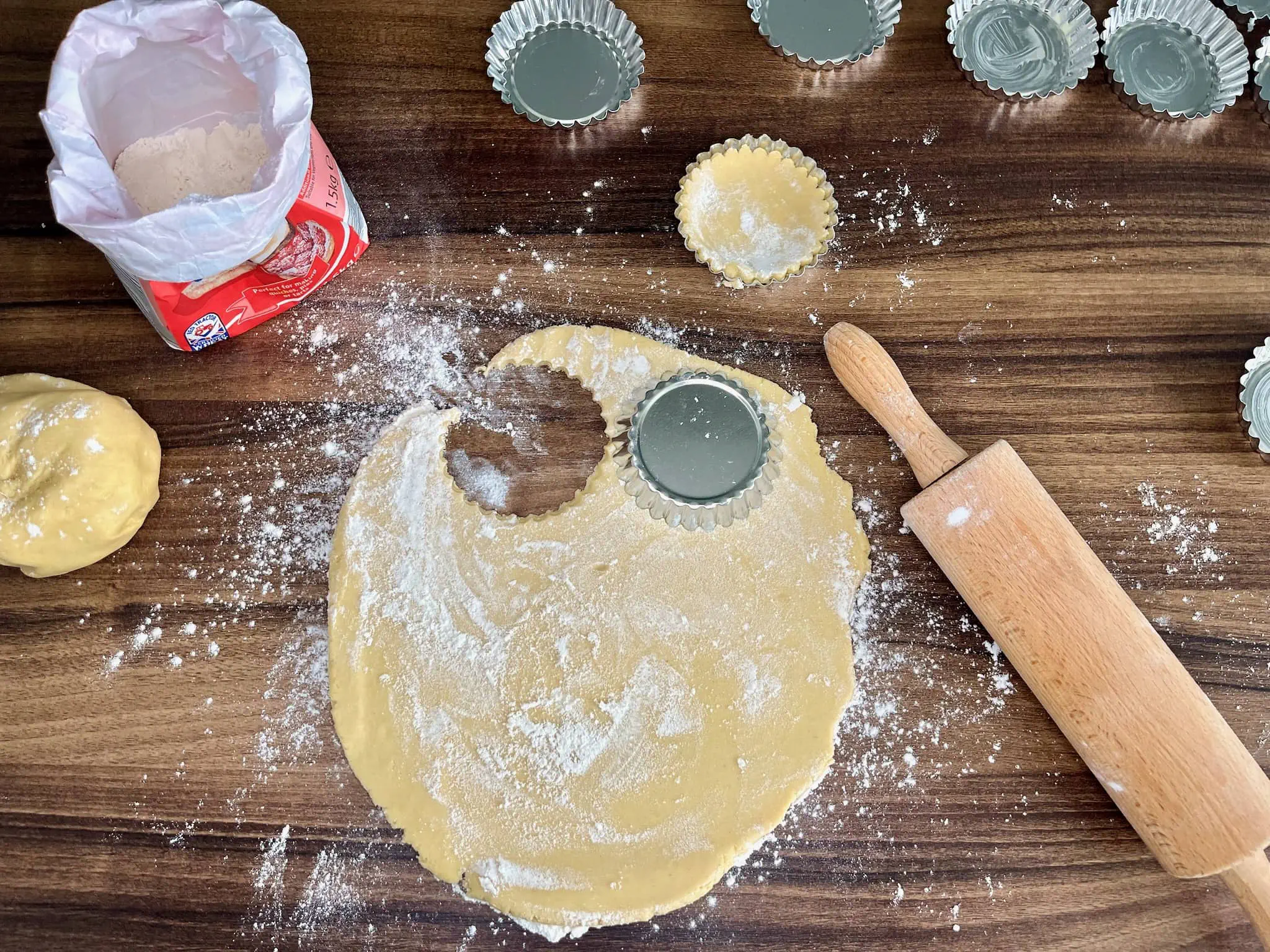 The dough has been rolled out and circles have been cut out using tart tins