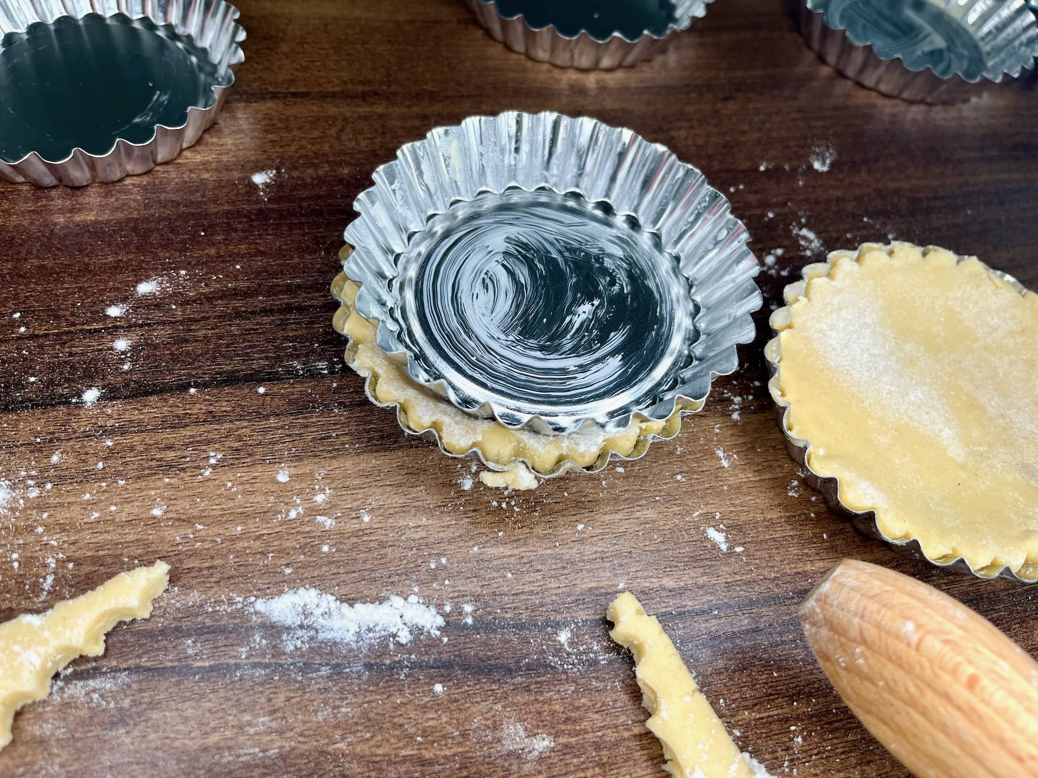 Making tart shells by pressing dough into a tart tin using the bottom of another tin