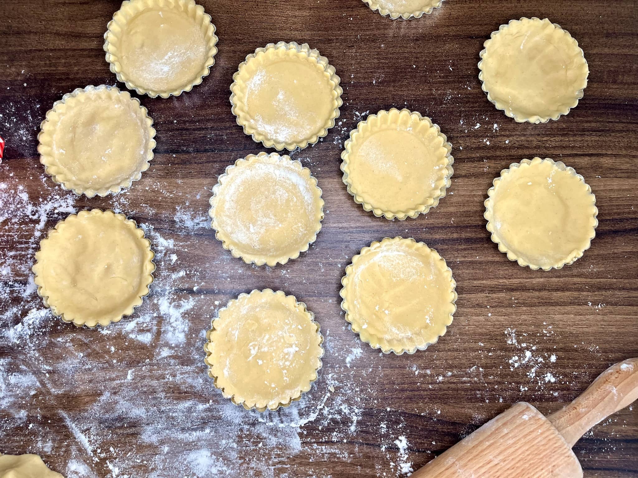 The tart shells are well-formed inside the tins and ready to be baked