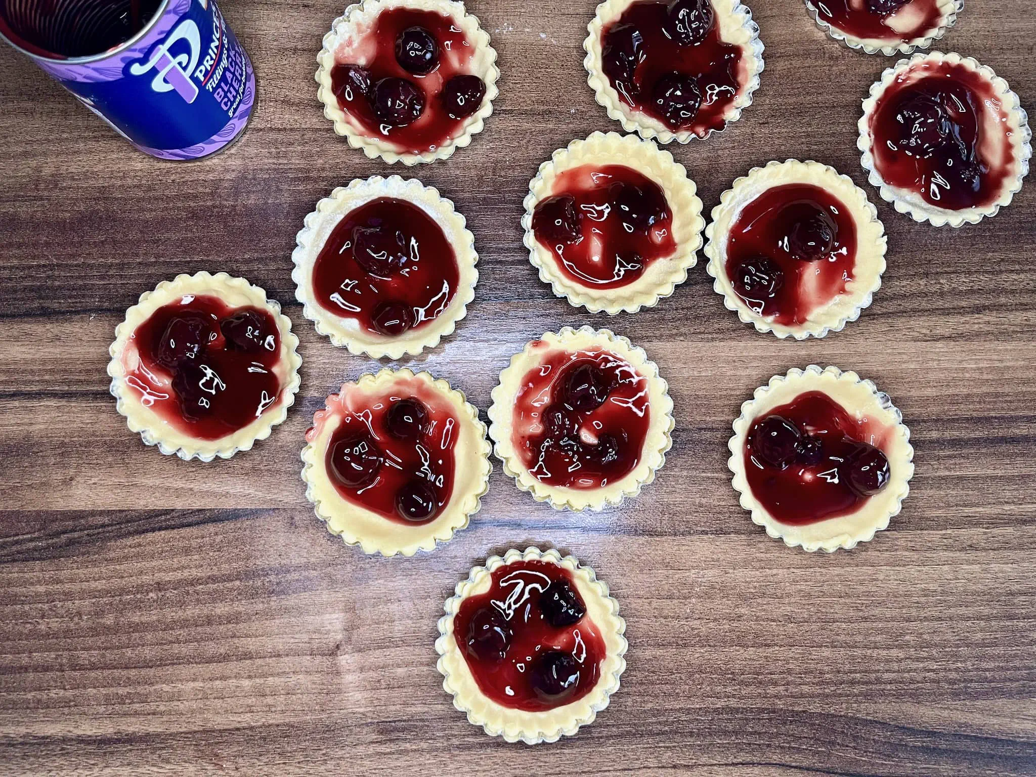 The tart shells have been filled with black cherry filling and are ready to be baked