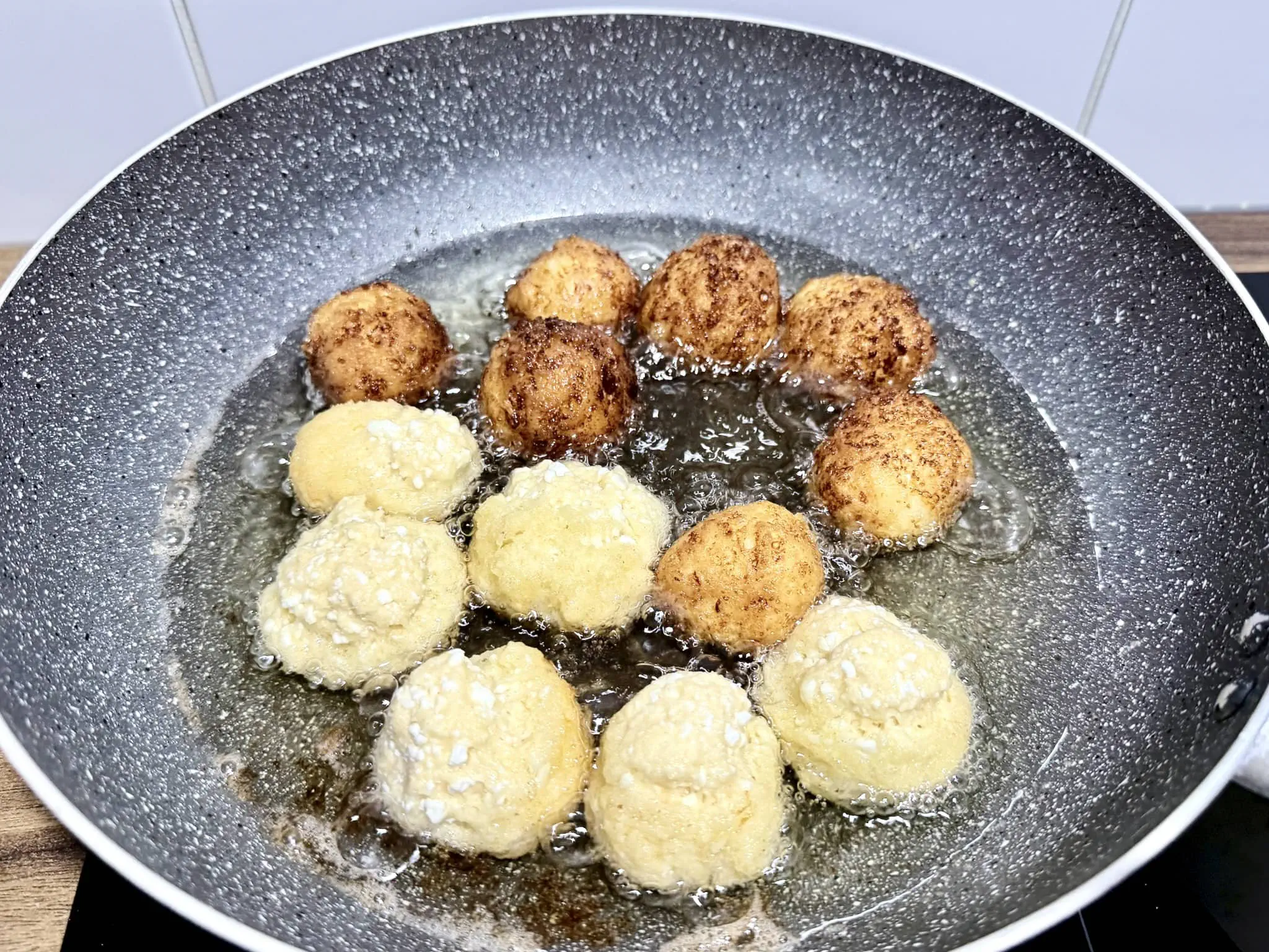 A portion of doughnut dough frying in a pan