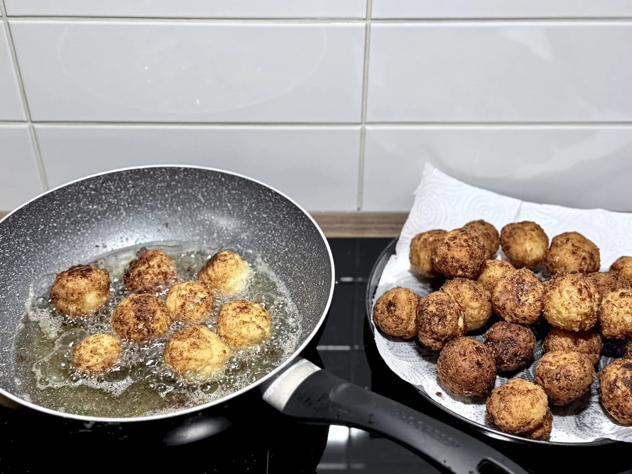 Some nicely fried doughnuts on the side, draining and cooling down while others fry in the pan