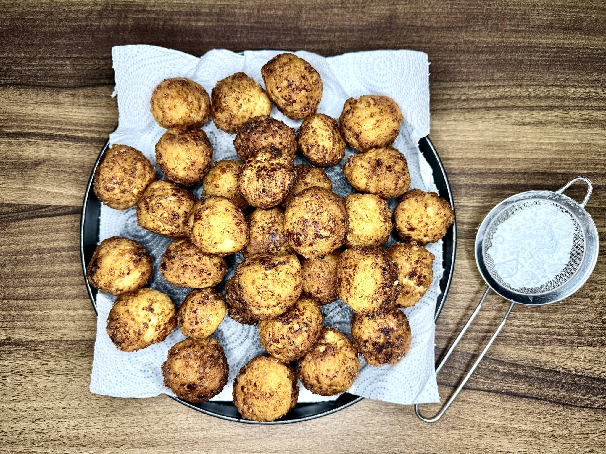 Nicely fried doughnuts on a plate with kitchen paper, cooling down before dusting with icing sugar