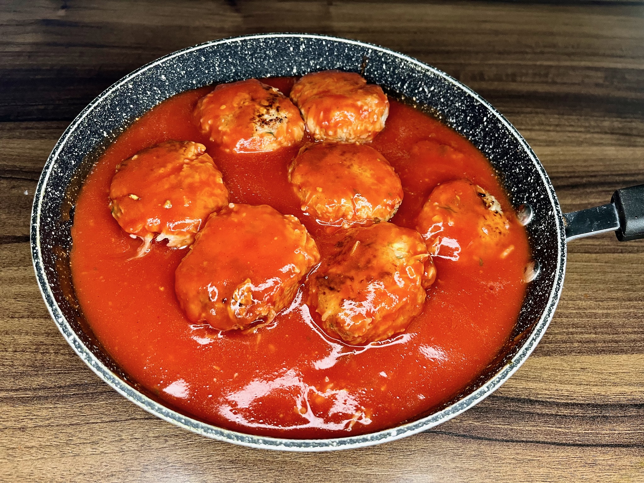 Fried gołąbki are in a deep pot, covered in a thick tomato sauce