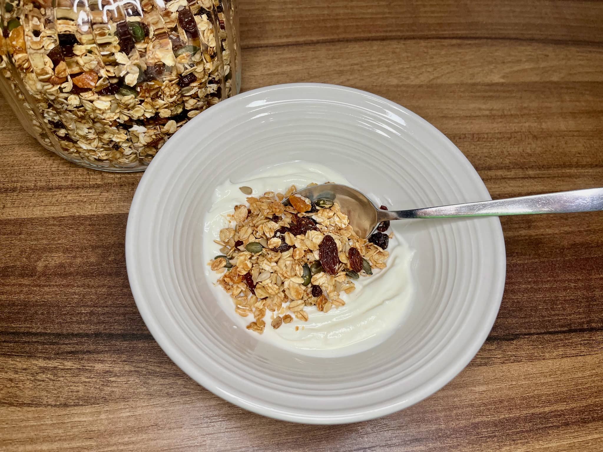 A portion of nut-free homemade granola on a plate with yoghurt