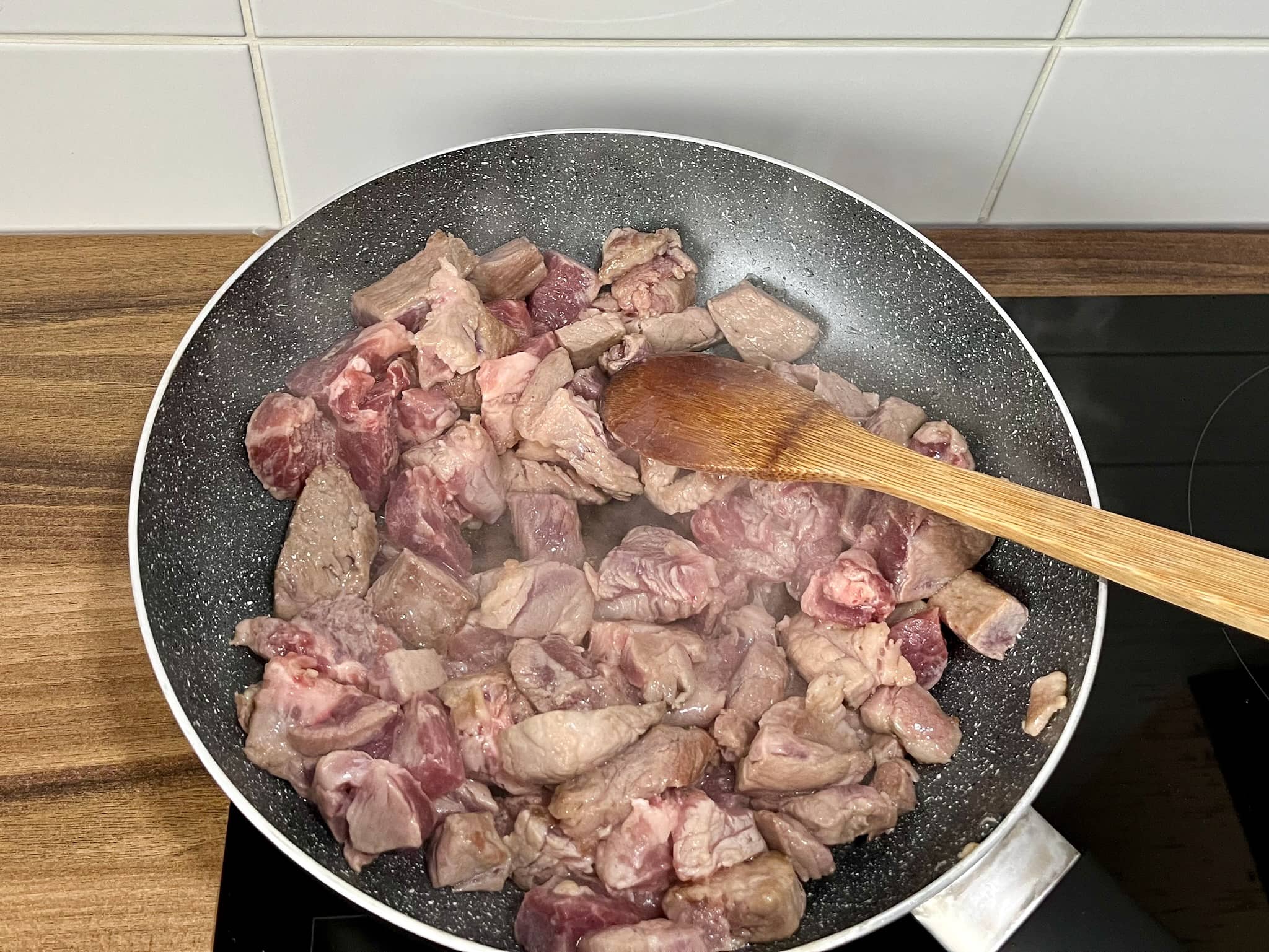 Chunks of pork frying in a pan