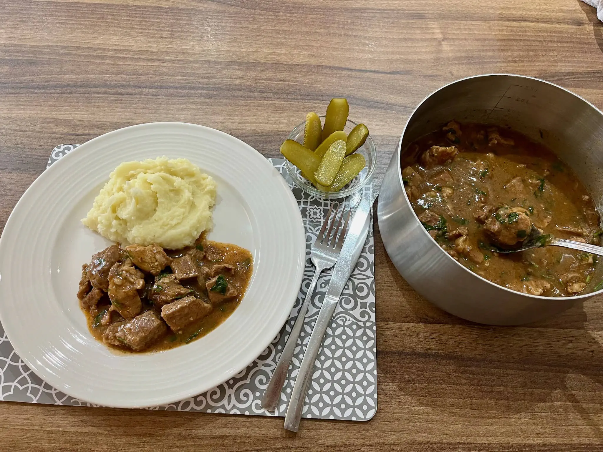 Gulasz wieprzowy podany z puree ziemniaczanym i ogórkami kiszonymi