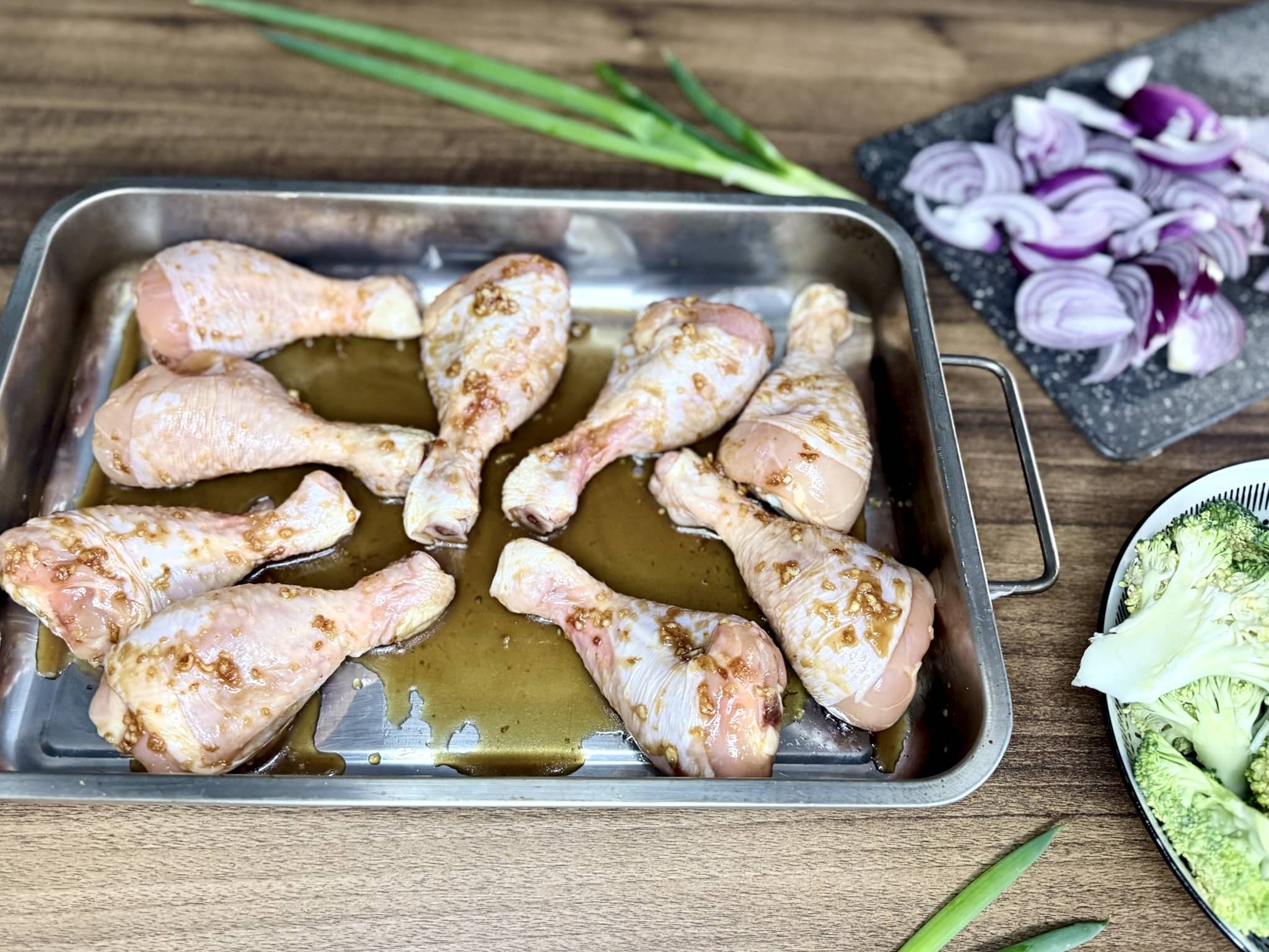 Chicken Drumsticks covered in marinade on a roasting tray before placing into the oven